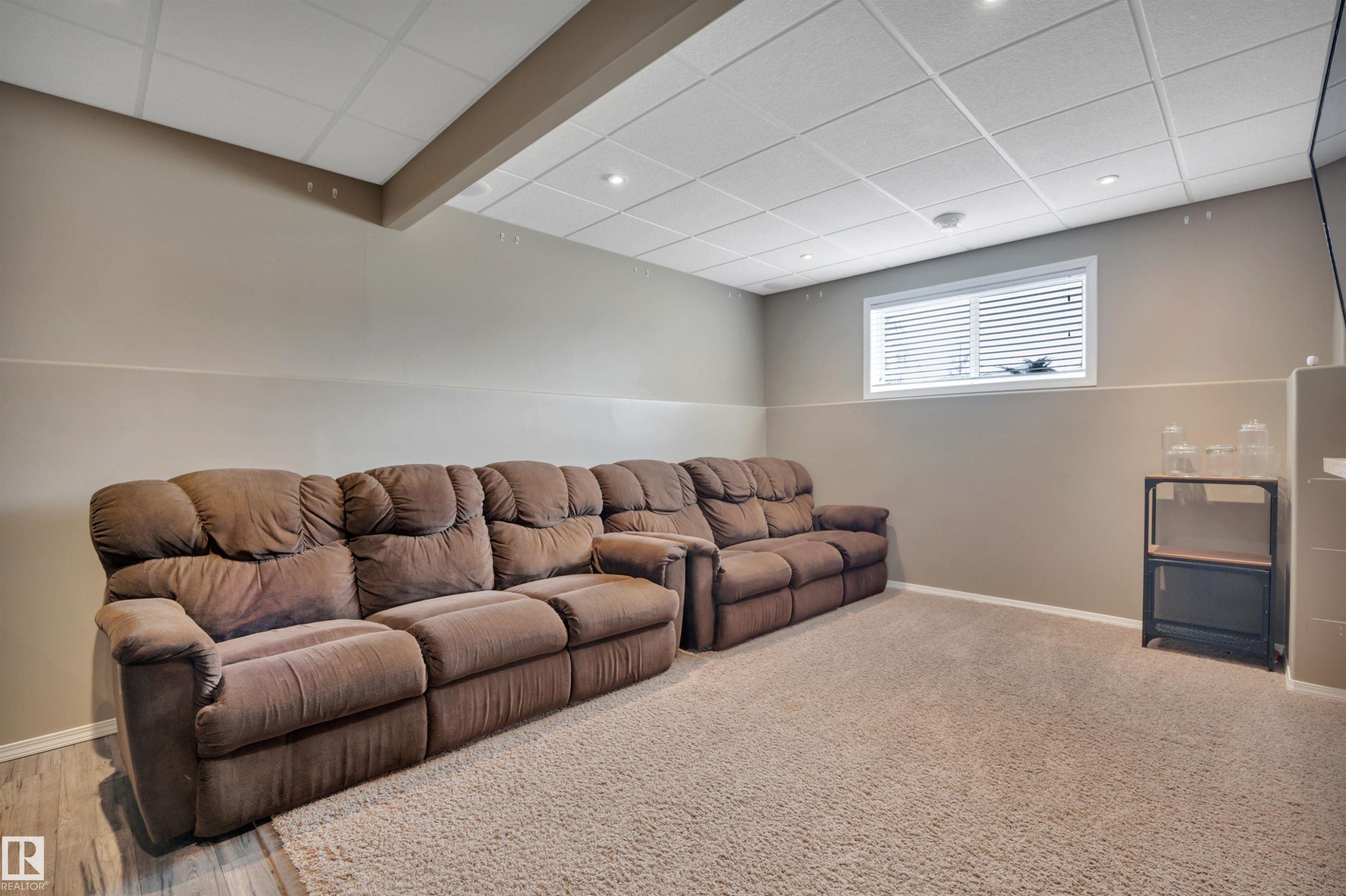 This inviting living area features a drop ceiling with recessed lighting, light-colored walls, and a window with blinds - 5 Parkview Crescent, Calmar, AB - Indoor Photo Showing Basement