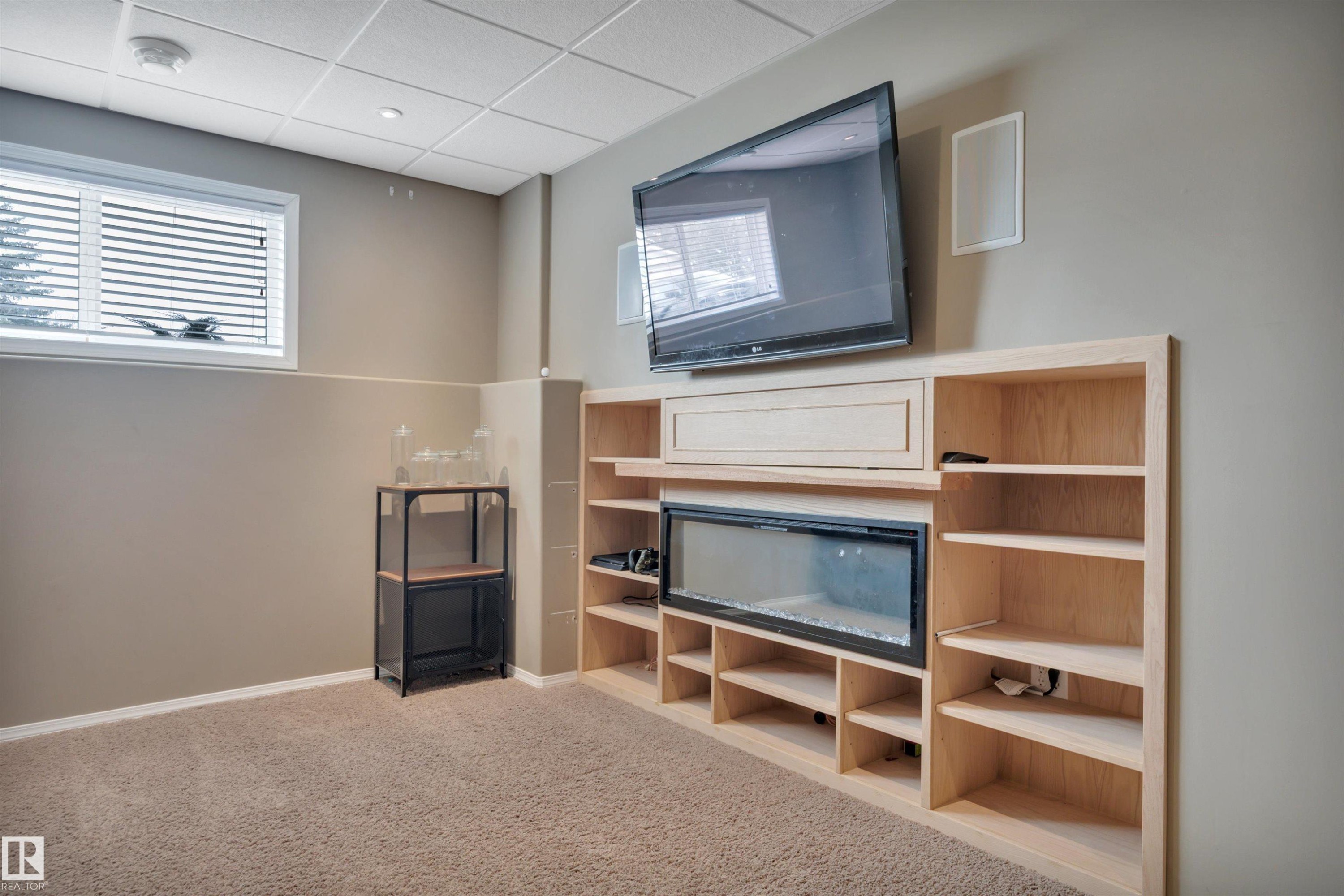 Living area featuring built-in shelving, an integrated fireplace, and a window with blinds - 5 Parkview Crescent, Calmar, AB - Indoor