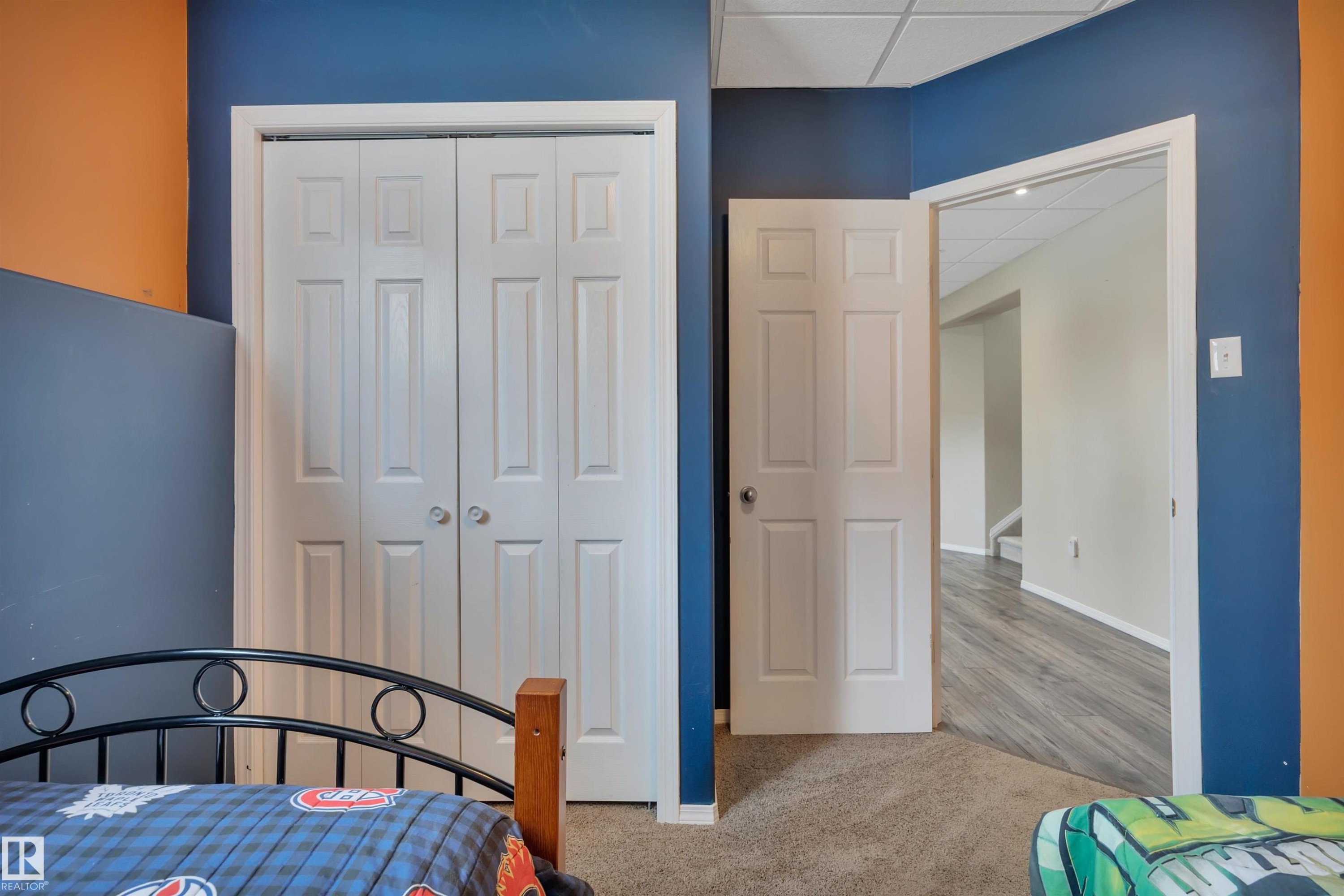 This room features a neutral carpet, white trim, and a combination of blue and orange painted walls - 5 Parkview Crescent, Calmar, AB - Indoor Photo Showing Bedroom