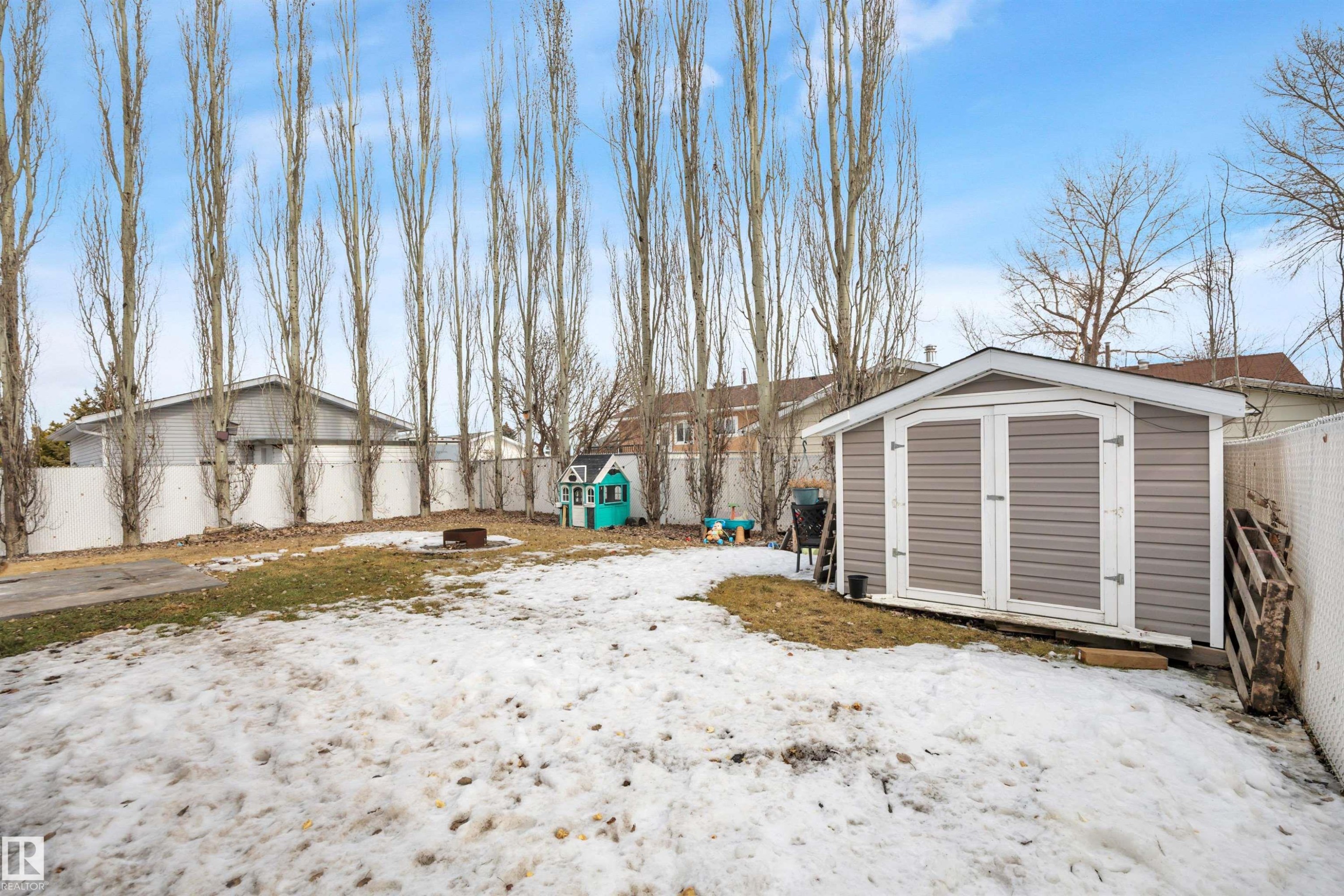 The property features a spacious yard with a storage shed and a white fence - 5 Parkview Crescent, Calmar, AB - Outdoor
