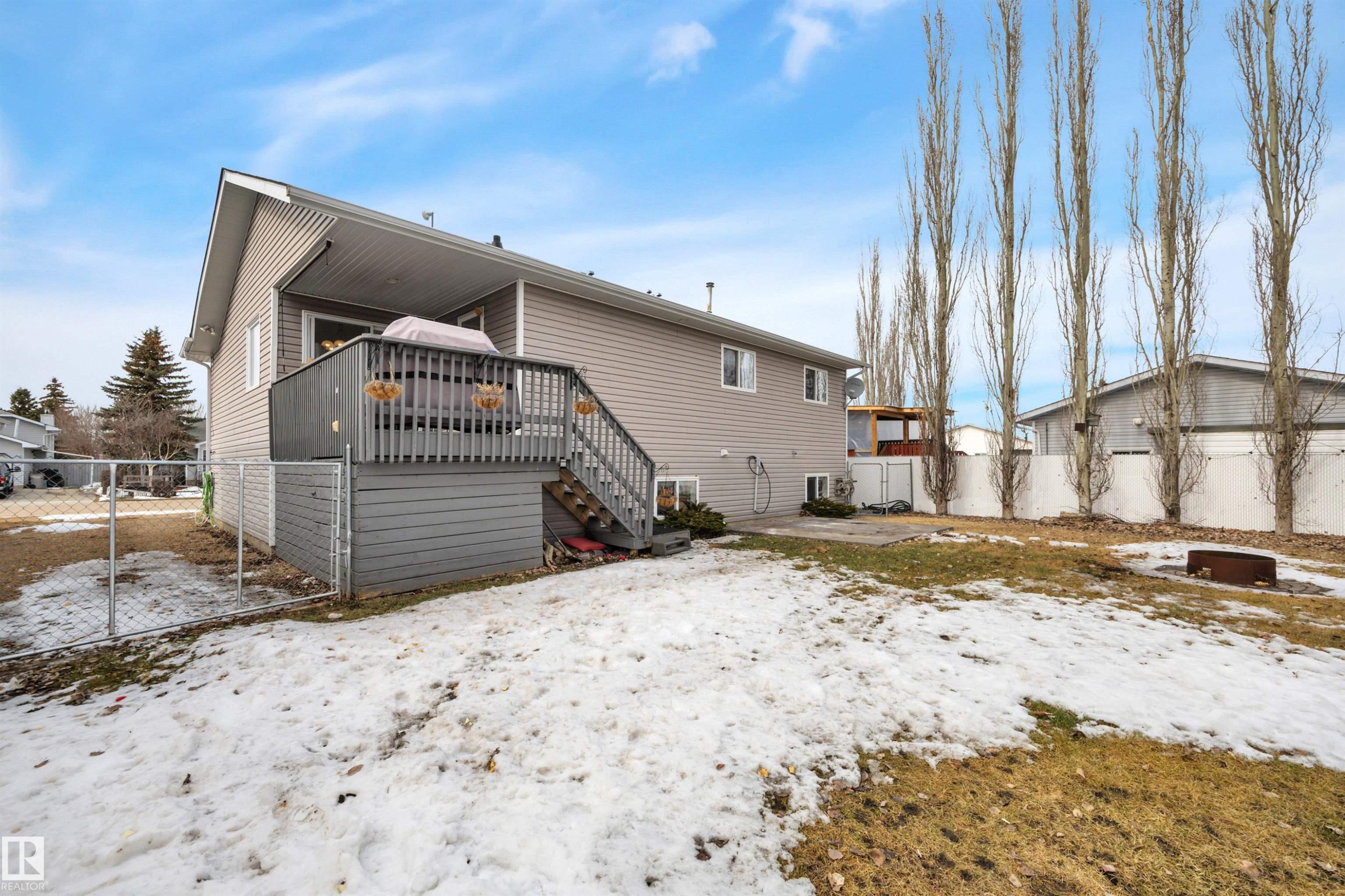The property features a spacious backyard with a deck, a fire pit, and a chain-link fence - 5 Parkview Crescent, Calmar, AB - Outdoor