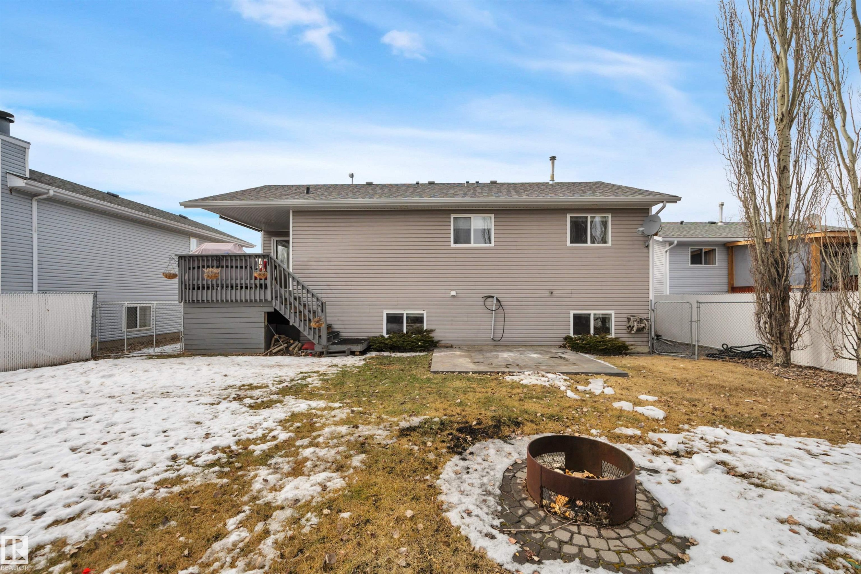 The property features a spacious backyard with a fire pit, a patio area, and a deck with stairs providing outdoor access - 5 Parkview Crescent, Calmar, AB - Outdoor With Exterior