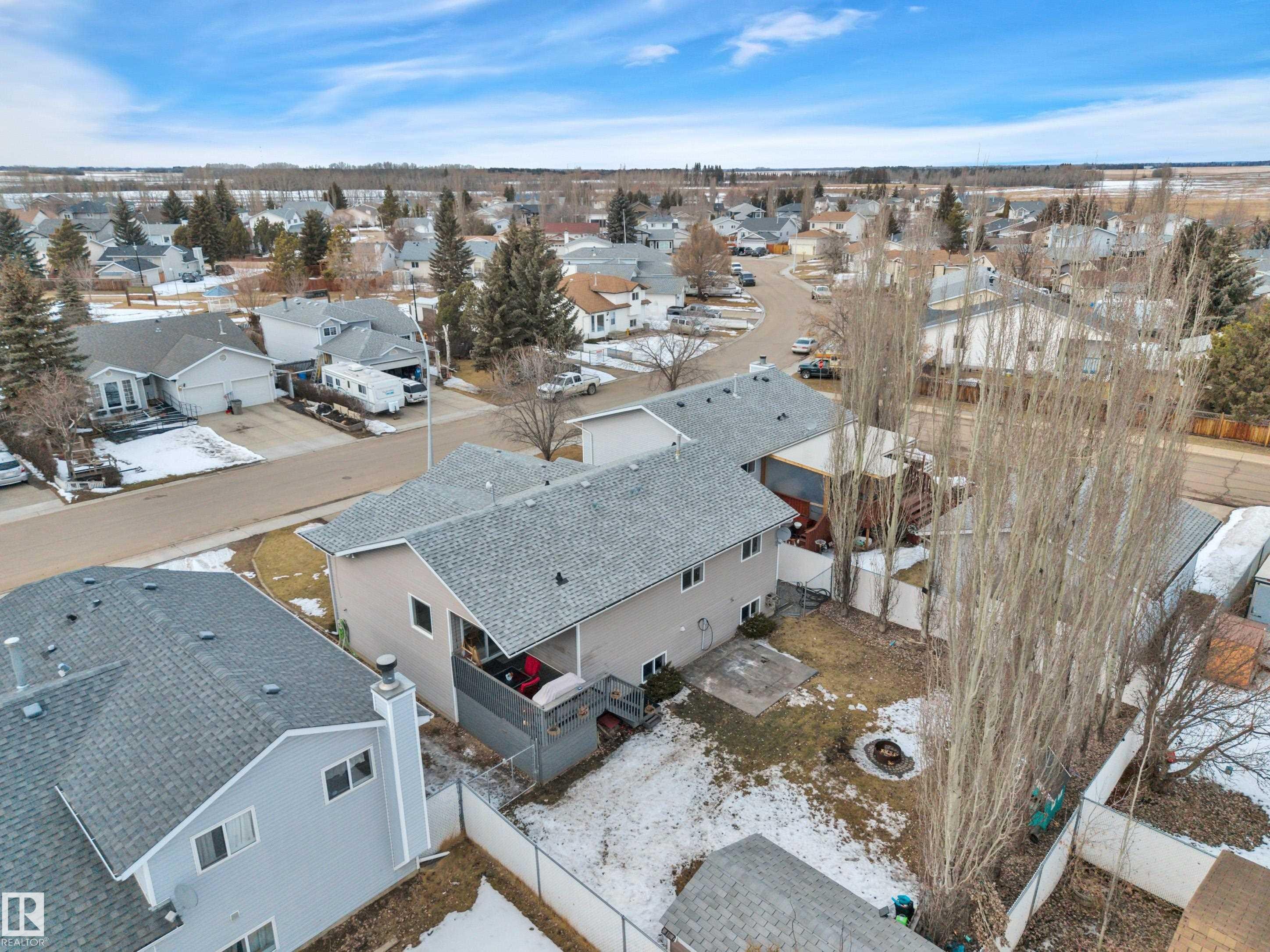 Aerial view of the property and surrounding neighborhood, featuring a fenced yard with a fire pit area, and a deck - 5 Parkview Crescent, Calmar, AB - Outdoor With View