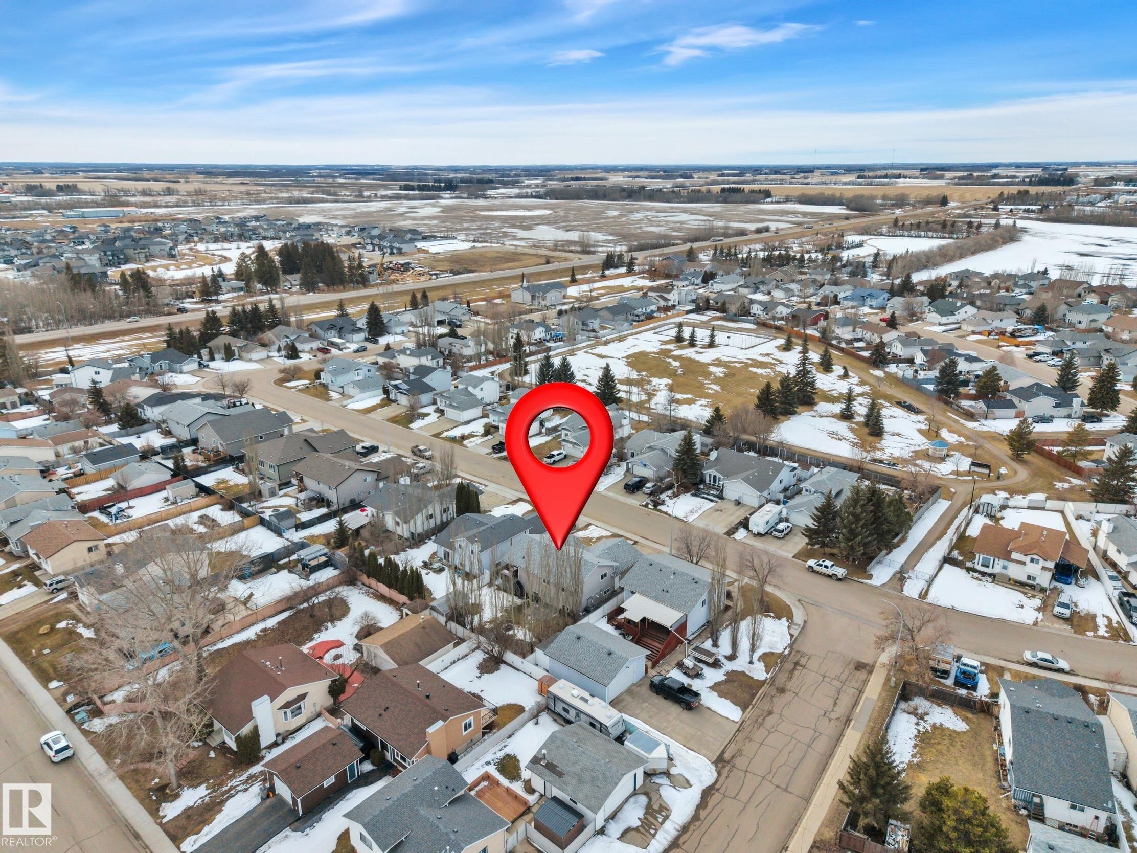 Aerial view of the property and its surrounding neighborhood, showcasing residential streets, detached homes, and open fields in the distance - 5 Parkview Crescent, Calmar, AB - Outdoor With View