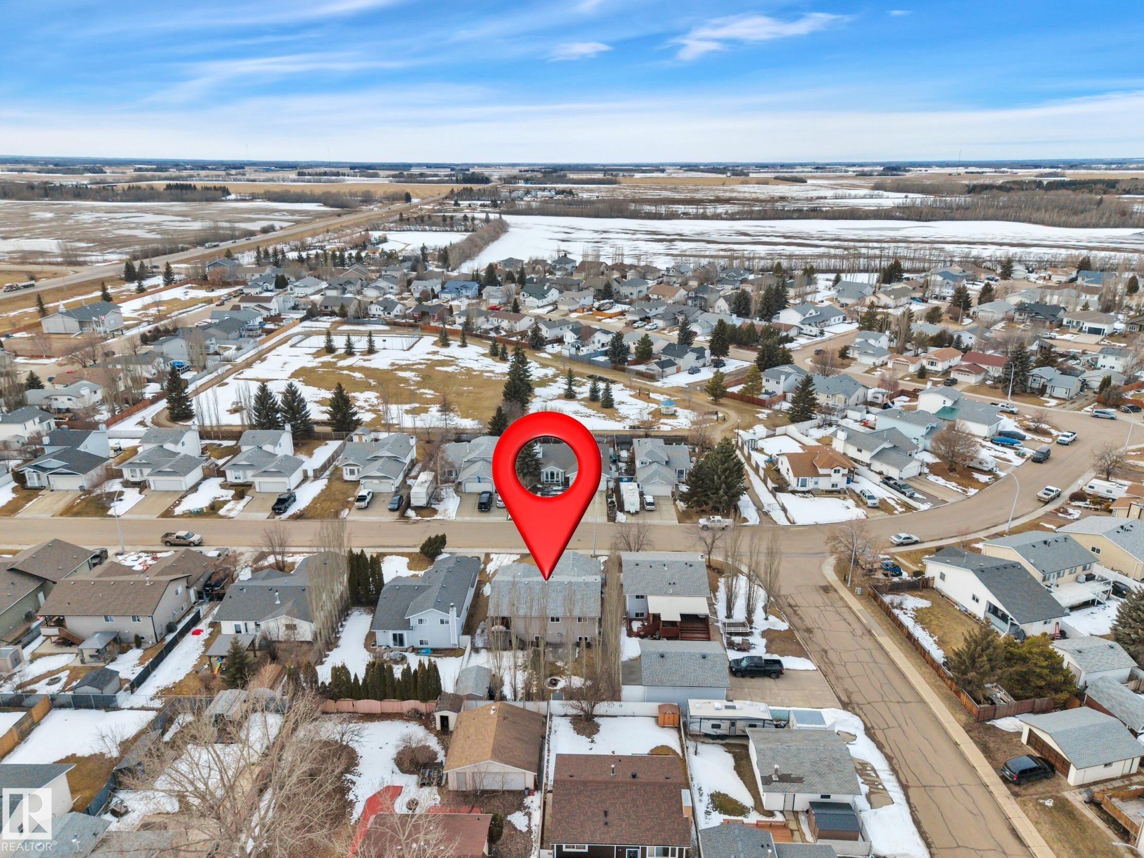 Aerial view showcasing the residential neighbourhood, surrounded by open fields and distant trees - 5 Parkview Crescent, Calmar, AB - Outdoor With View