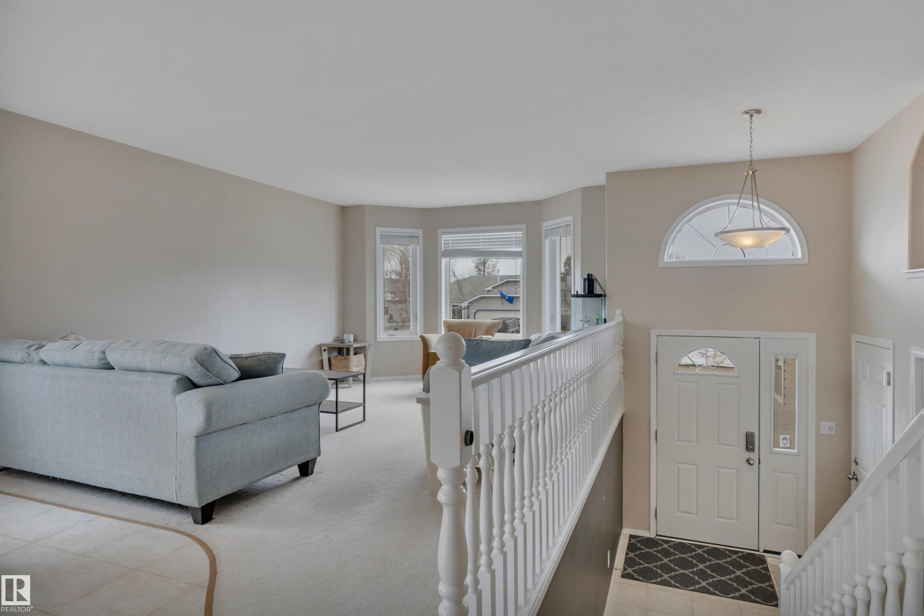 The property features an entryway with a white door, a half-moon window above, and a hanging light fixture - 5 Parkview Crescent, Calmar, AB - Indoor