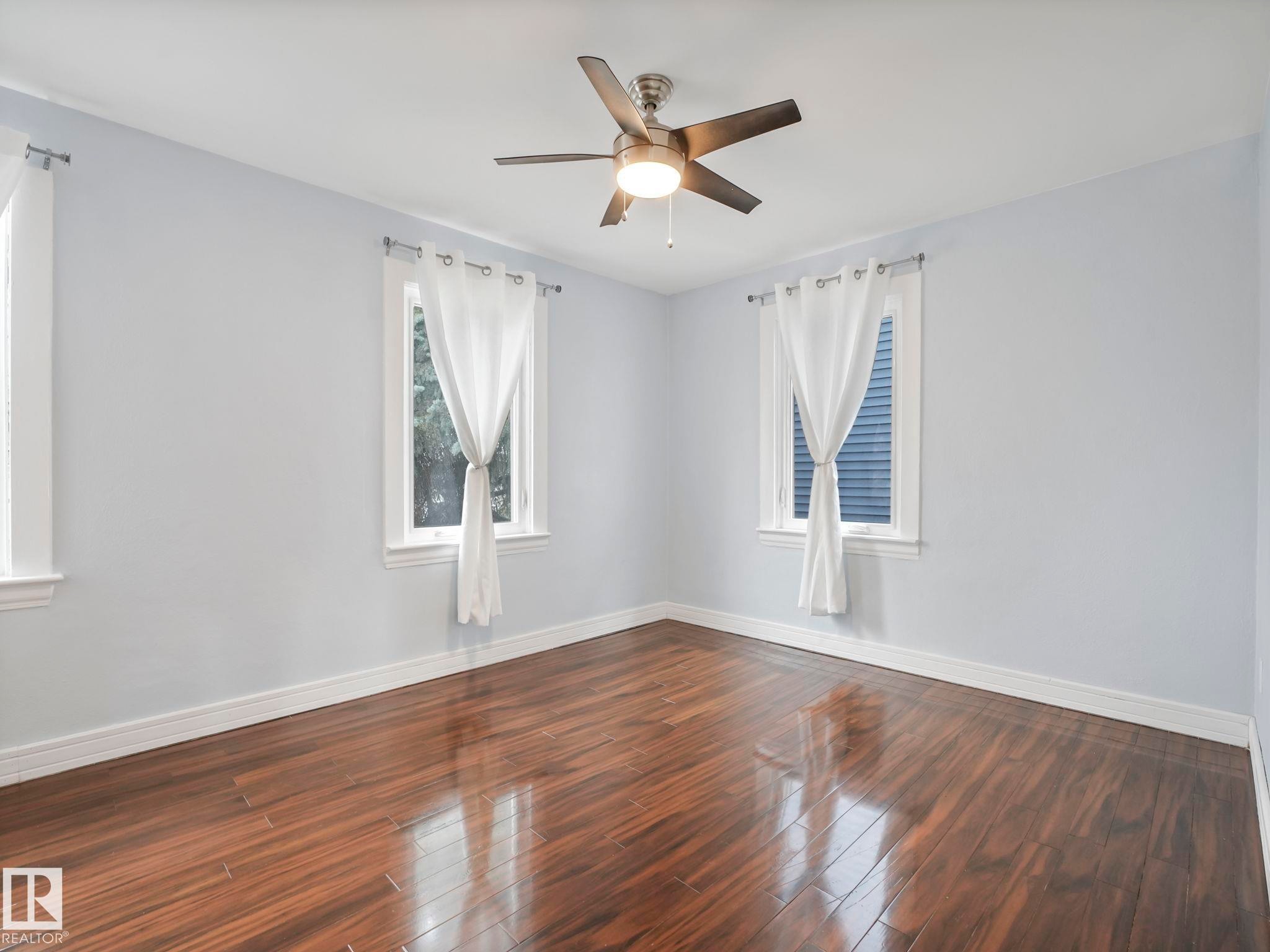 This room features hardwood flooring, light-colored walls, and a ceiling fan - 12141 96 Street, Edmonton, AB - Indoor Photo Showing Other Room