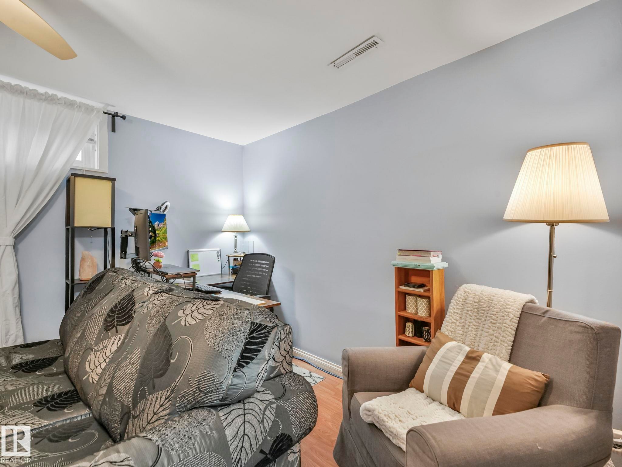 This room features light blue walls, a ceiling fan, and window with white curtains - 12141 96 Street, Edmonton, AB - Indoor