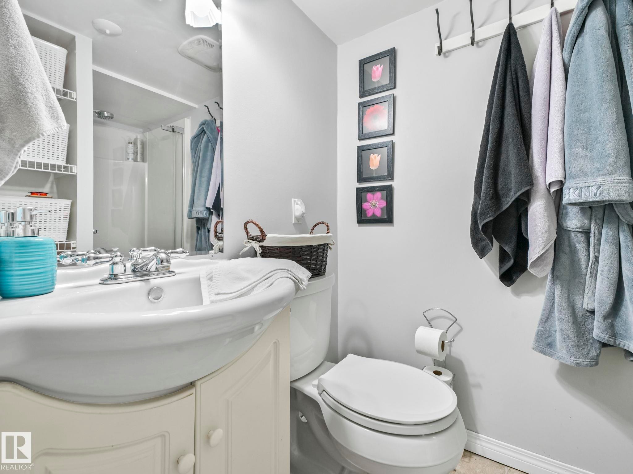 The bathroom features a white vanity with a porcelain sink, a toilet, and a shower with a clear glass enclosure - 12141 96 Street, Edmonton, AB - Indoor Photo Showing Bathroom