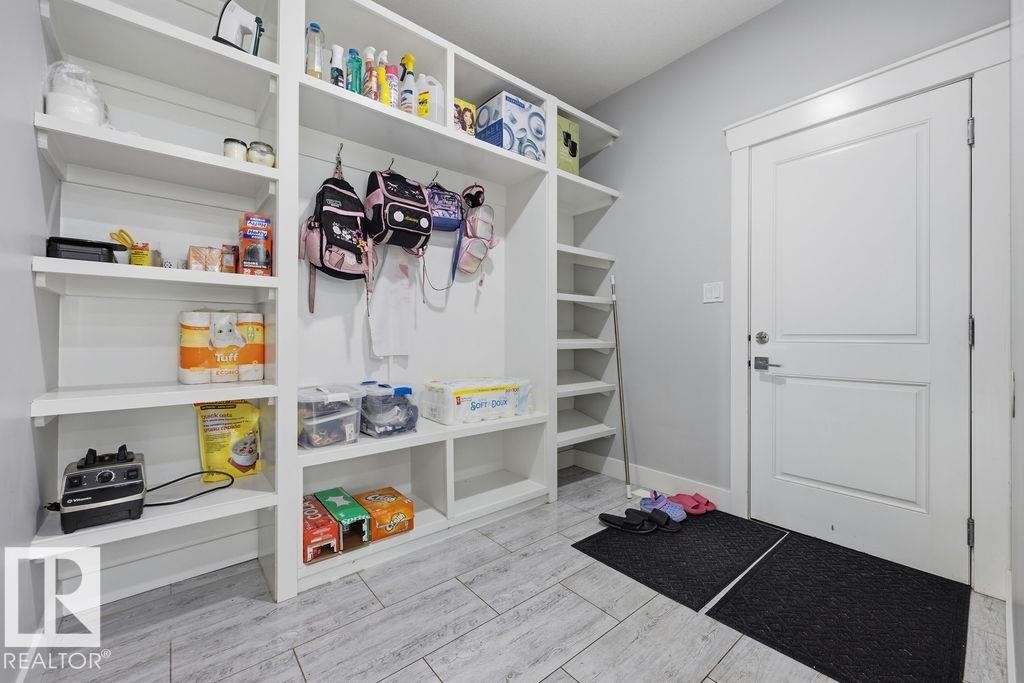 Mudroom featuring extensive white built-in shelving, a white door with a silver handle, and light-colored tile flooring - 17534 60A Street, Edmonton, AB - Indoor With Storage