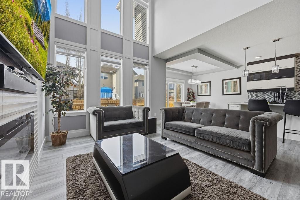 This open-concept living space features high ceilings, large windows, and light flooring - 17534 60A Street, Edmonton, AB - Indoor Photo Showing Living Room With Fireplace