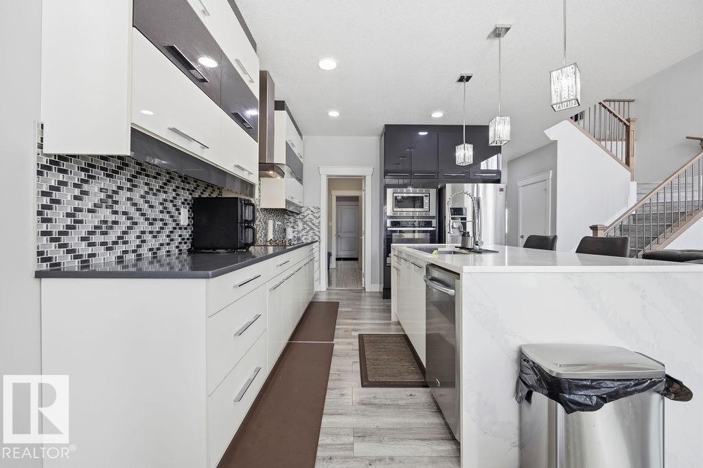 The kitchen features white cabinetry with polished chrome hardware, a patterned tile backsplash, and dark countertops - 17534 60A Street, Edmonton, AB - Indoor Photo Showing Kitchen With Upgraded Kitchen