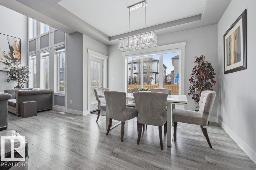 The open-concept living and dining area features high ceilings, extensive windows, and light wood-style flooring - 17534 60A Street, Edmonton, AB - Indoor Photo Showing Dining Room