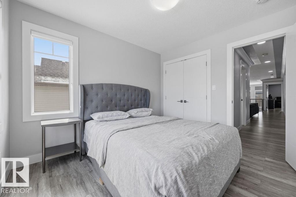 Bedroom featuring light gray walls, a window with white trim, a closet with double doors, and wood-style flooring - 17534 60A Street, Edmonton, AB - Indoor Photo Showing Bedroom