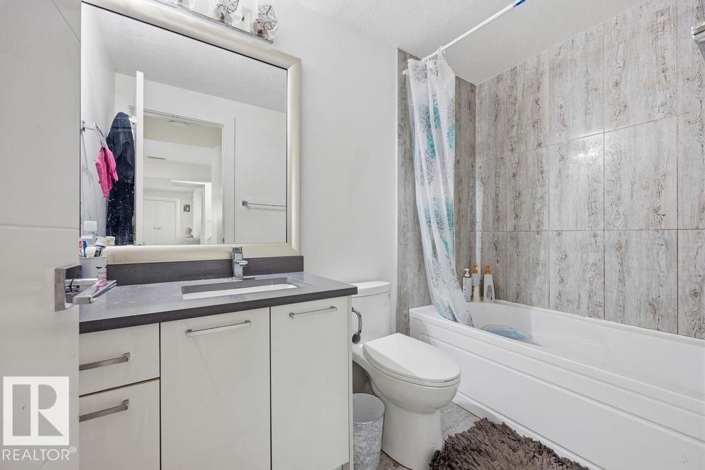 Bathroom featuring a white vanity with a dark countertop, a mirror with a decorative frame, and a bathtub with textured wall tiles - 17534 60A Street, Edmonton, AB - Indoor Photo Showing Bathroom