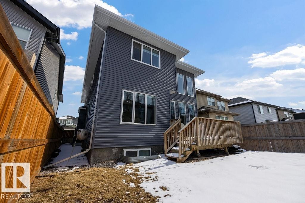 The property features grey horizontal siding, a wooden deck with railing and steps, and a fenced yard - 17534 60A Street, Edmonton, AB - Outdoor With Exterior