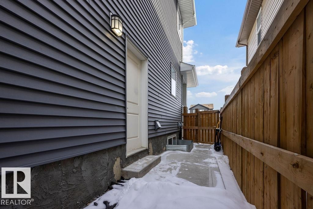 The property features dark gray horizontal siding and a white exterior door with a light fixture - 17534 60A Street, Edmonton, AB - Outdoor With Exterior