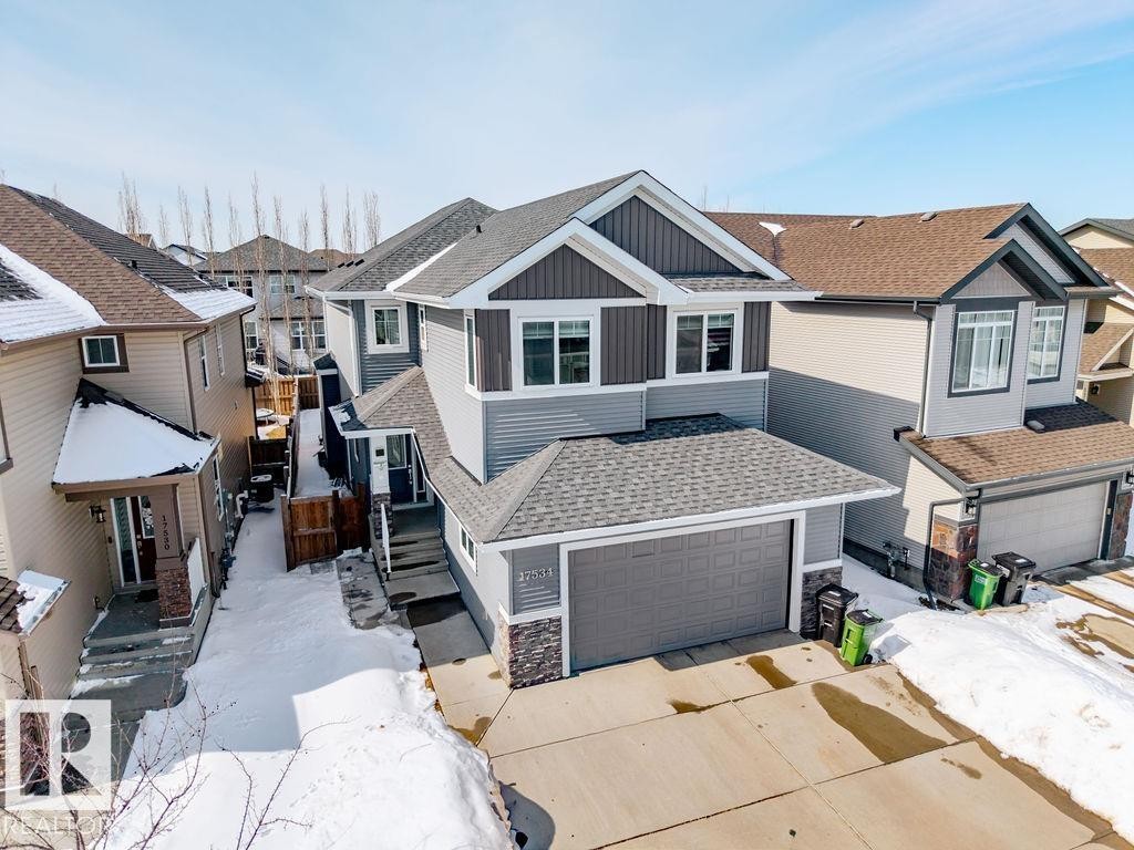 The property features a two-story design with a gray and brown exterior, a dark gray shingled roof, and an attached garage with a gray door - 17534 60A Street, Edmonton, AB - Outdoor With Facade