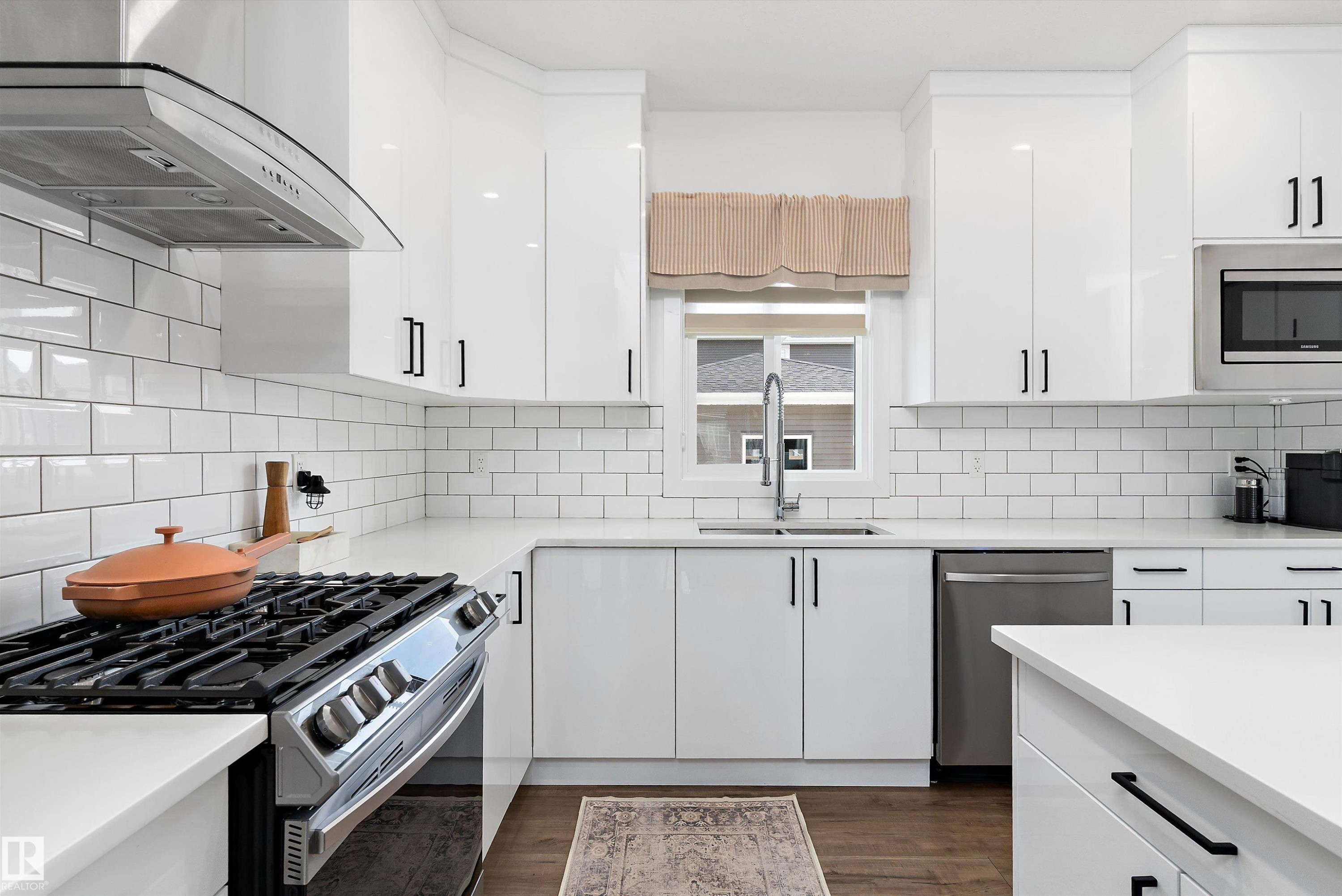 The kitchen features white shaker-style cabinetry with black hardware, white subway tile backsplash, and stainless steel appliances - 1305 Enright Landing, Edmonton, AB - Indoor Photo Showing Kitchen With Double Sink With Upgraded Kitchen