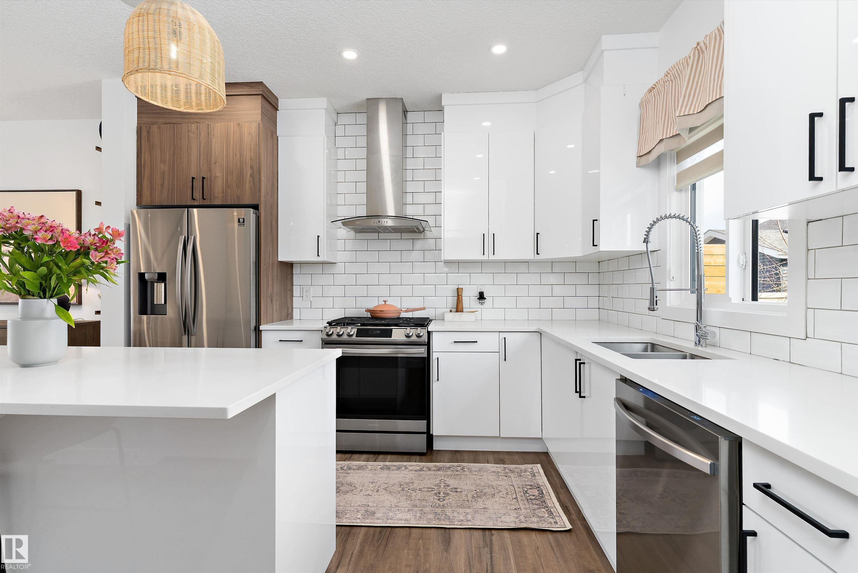 Modern kitchen featuring white cabinetry, subway tile backsplash, stainless steel appliances, and a central island with a white countertop - 1305 Enright Landing, Edmonton, AB - Indoor Photo Showing Kitchen With Stainless Steel Kitchen With Double Sink With Upgraded Kitchen