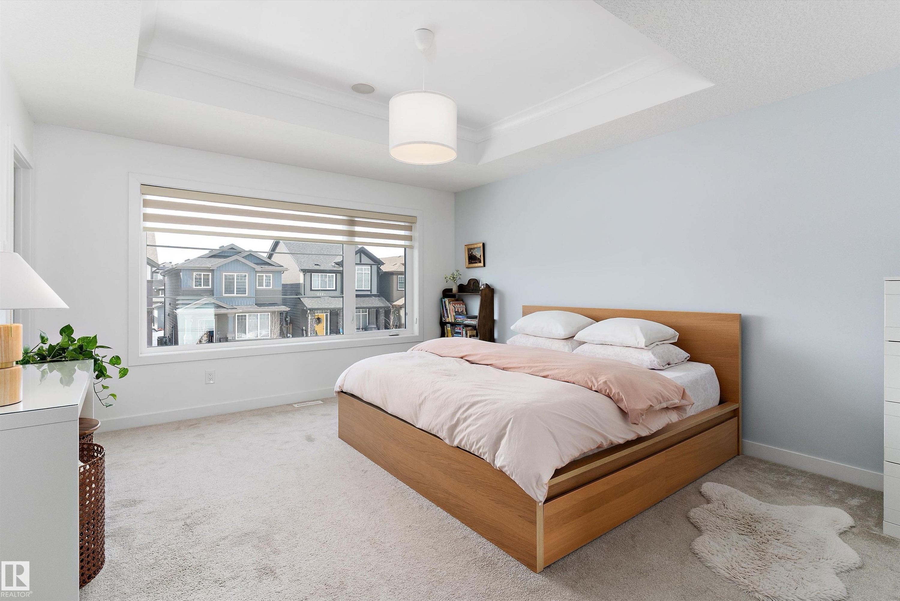 This room features a tray ceiling, light-colored walls, and a large window with blinds - 1305 Enright Landing, Edmonton, AB - Indoor Photo Showing Bedroom