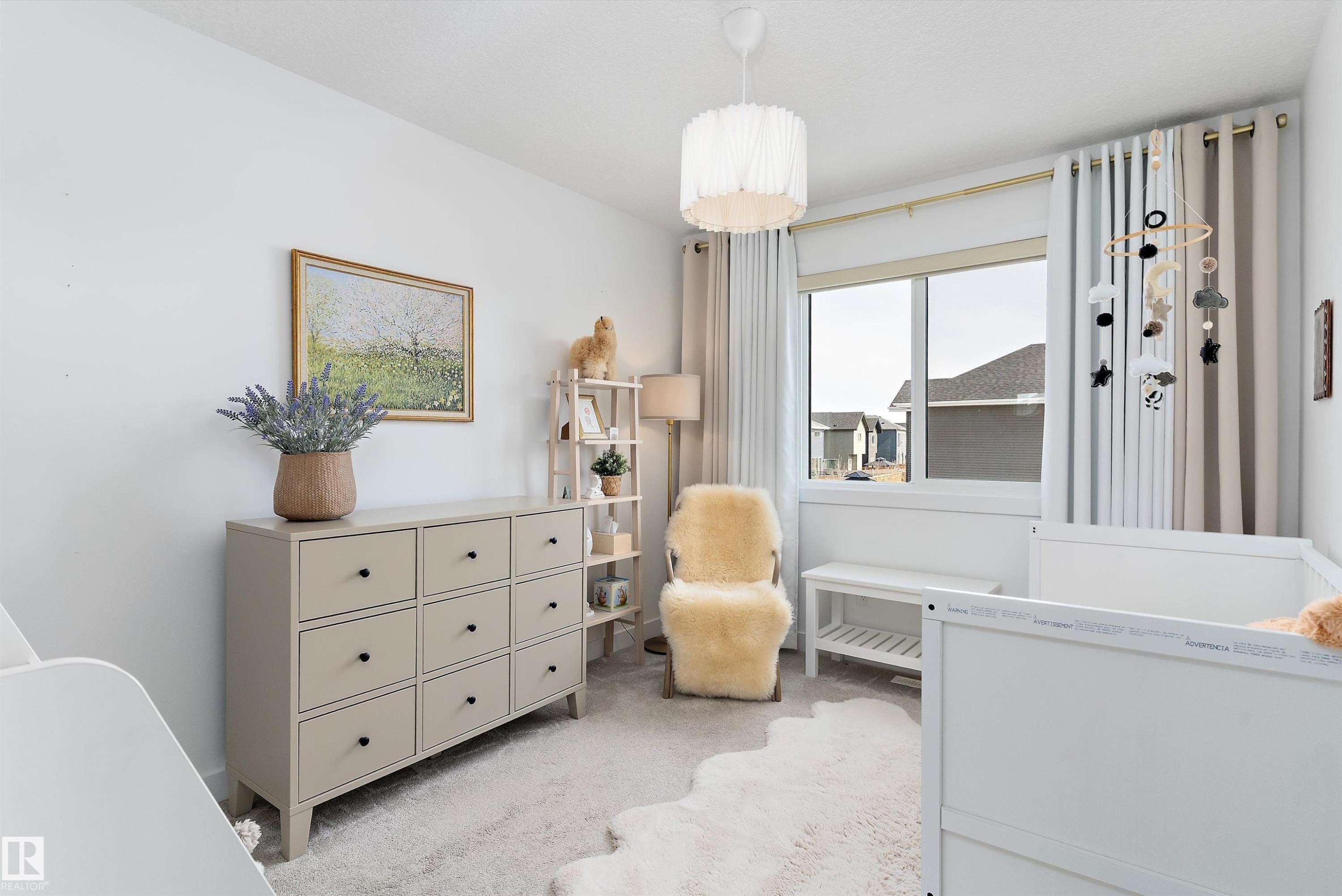 This bright room features a window with blinds and curtains, a light-colored carpet, and a decorative ceiling light fixture - 1305 Enright Landing, Edmonton, AB - Indoor Photo Showing Bedroom
