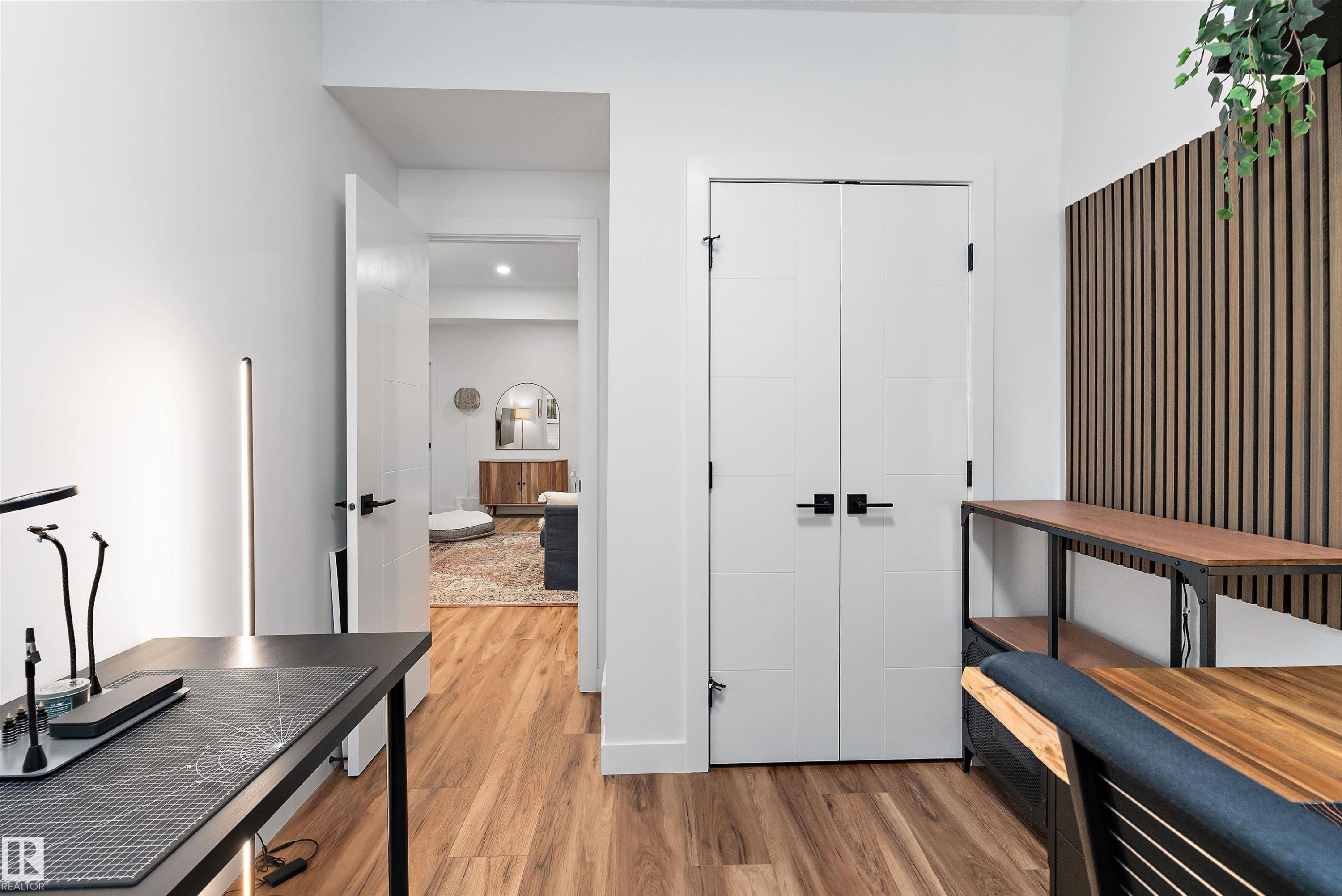 This interior space features hardwood flooring, white walls, and a modern accent wall with vertical wood slats - 1305 Enright Landing, Edmonton, AB - Indoor