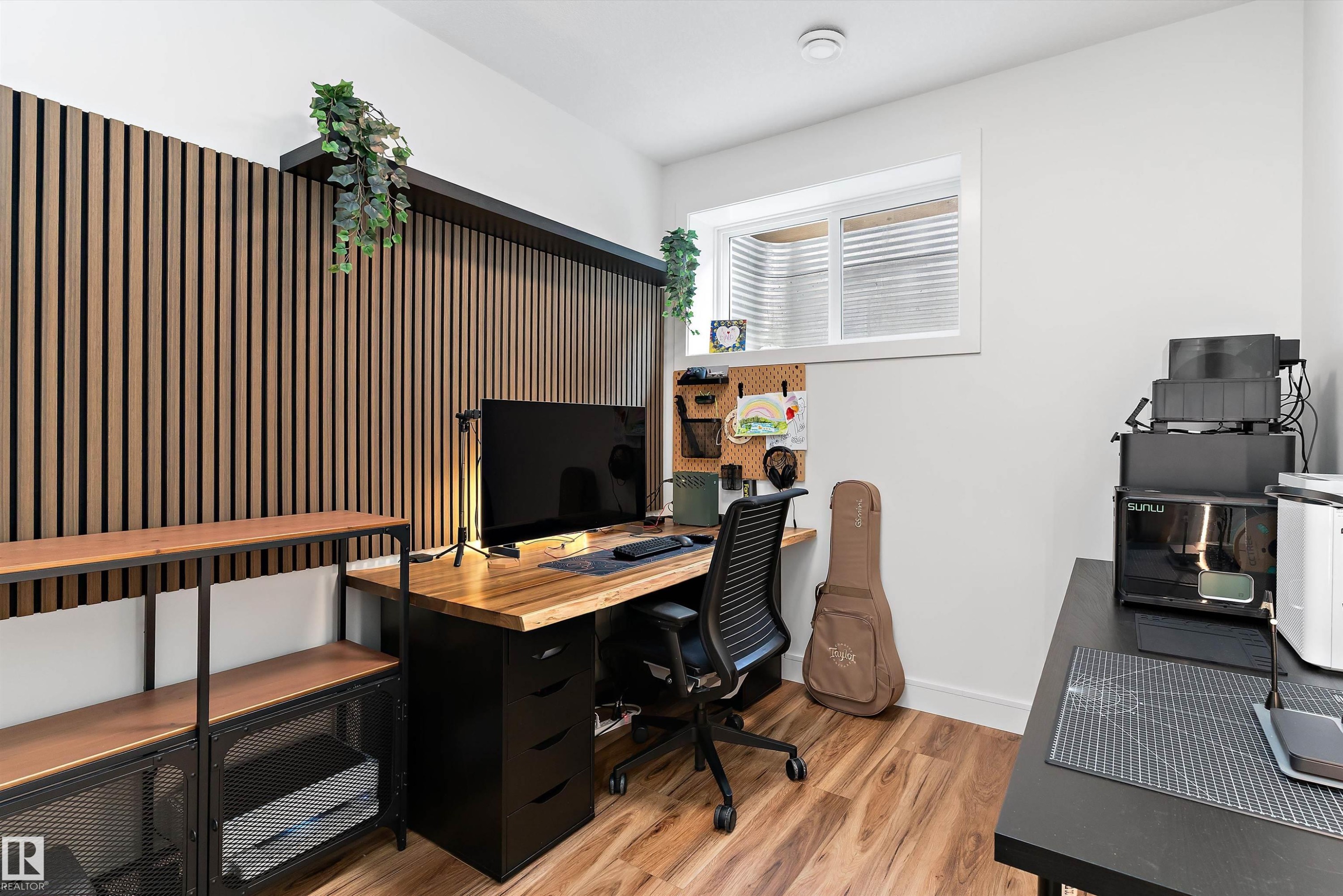 The room features wood-look flooring, a window, and a decorative slatted wood wall panel - 1305 Enright Landing, Edmonton, AB - Indoor Photo Showing Office