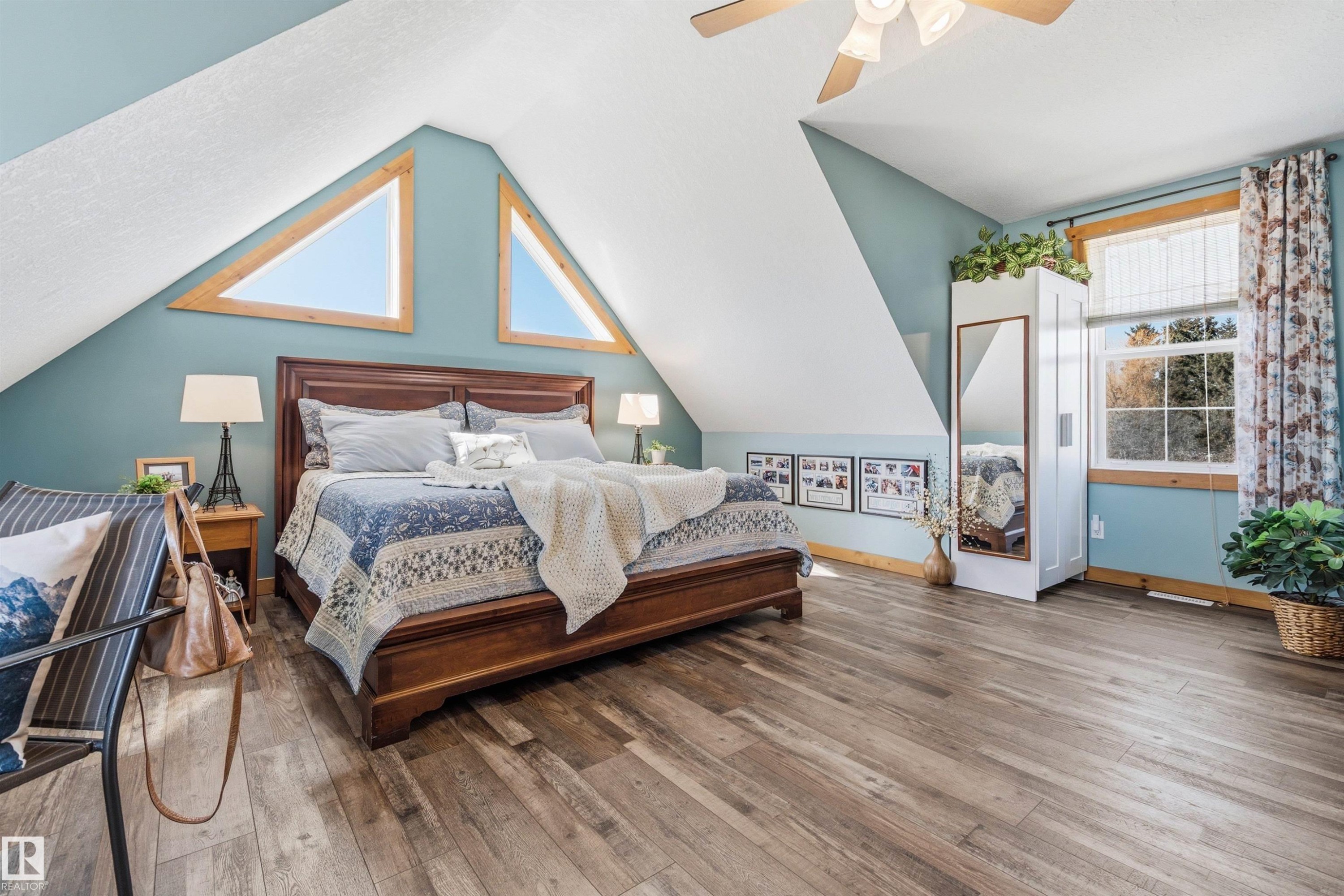 Spacious bedroom featuring light wood flooring, unique triangular windows, and a ceiling fan - 17 Sunset Harbour, Rural Wetaskiwin County, AB - Indoor Photo Showing Bedroom