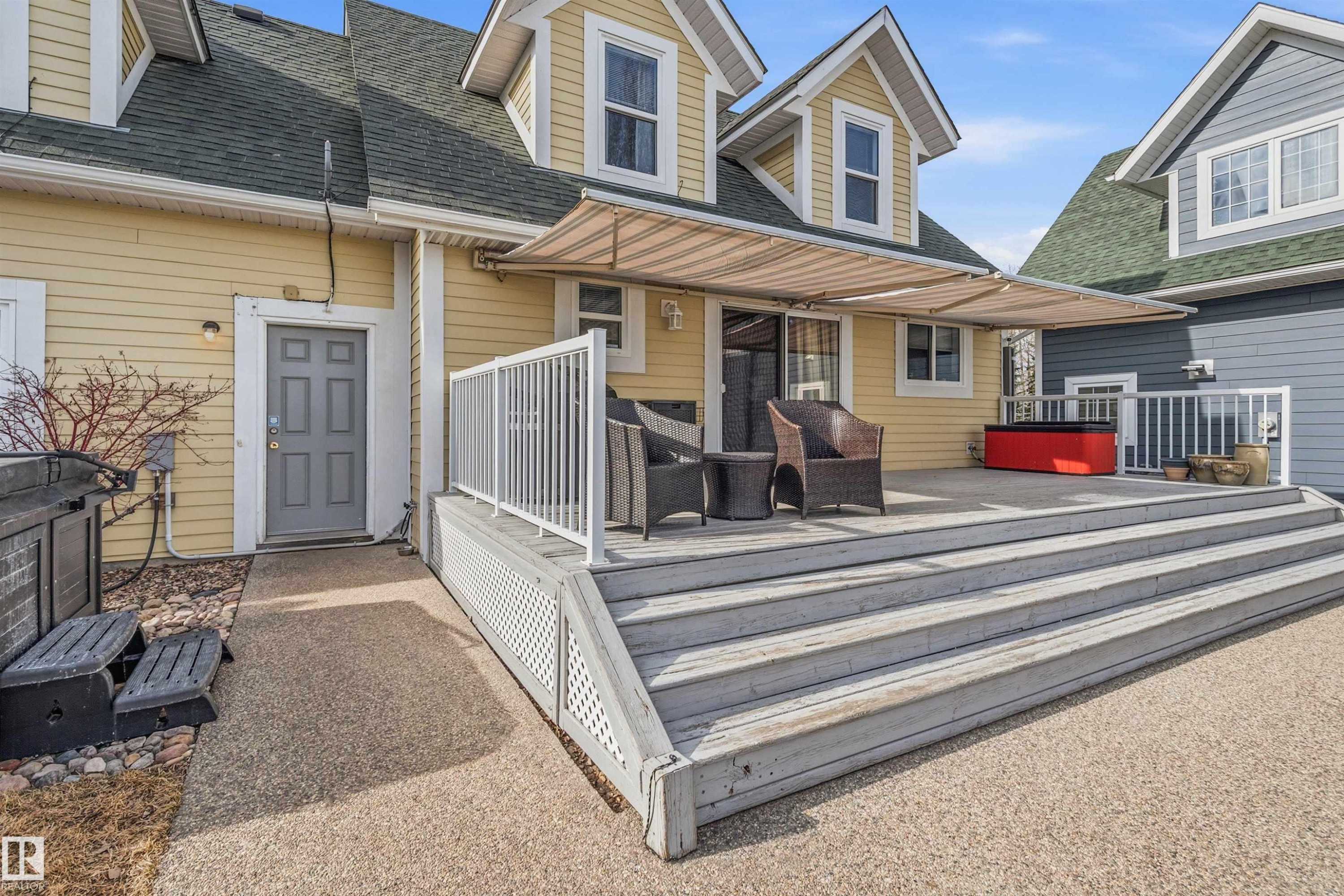 The property features an outdoor deck with a retractable awning, accessible via sliding glass doors - 17 Sunset Harbour, Rural Wetaskiwin County, AB - Outdoor