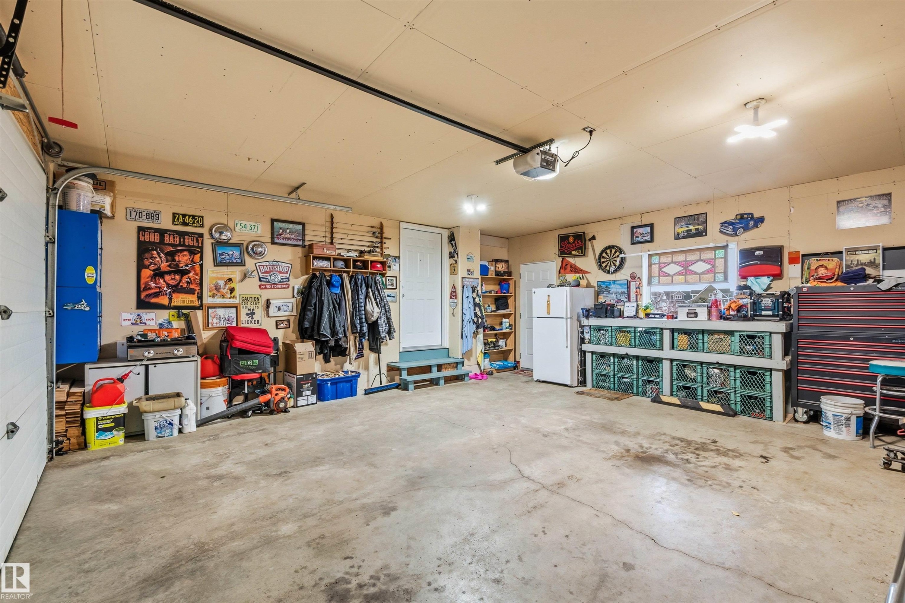 This expansive garage features a concrete floor, a white overhead door, and recessed lighting - 17 Sunset Harbour, Rural Wetaskiwin County, AB - Indoor Photo Showing Garage