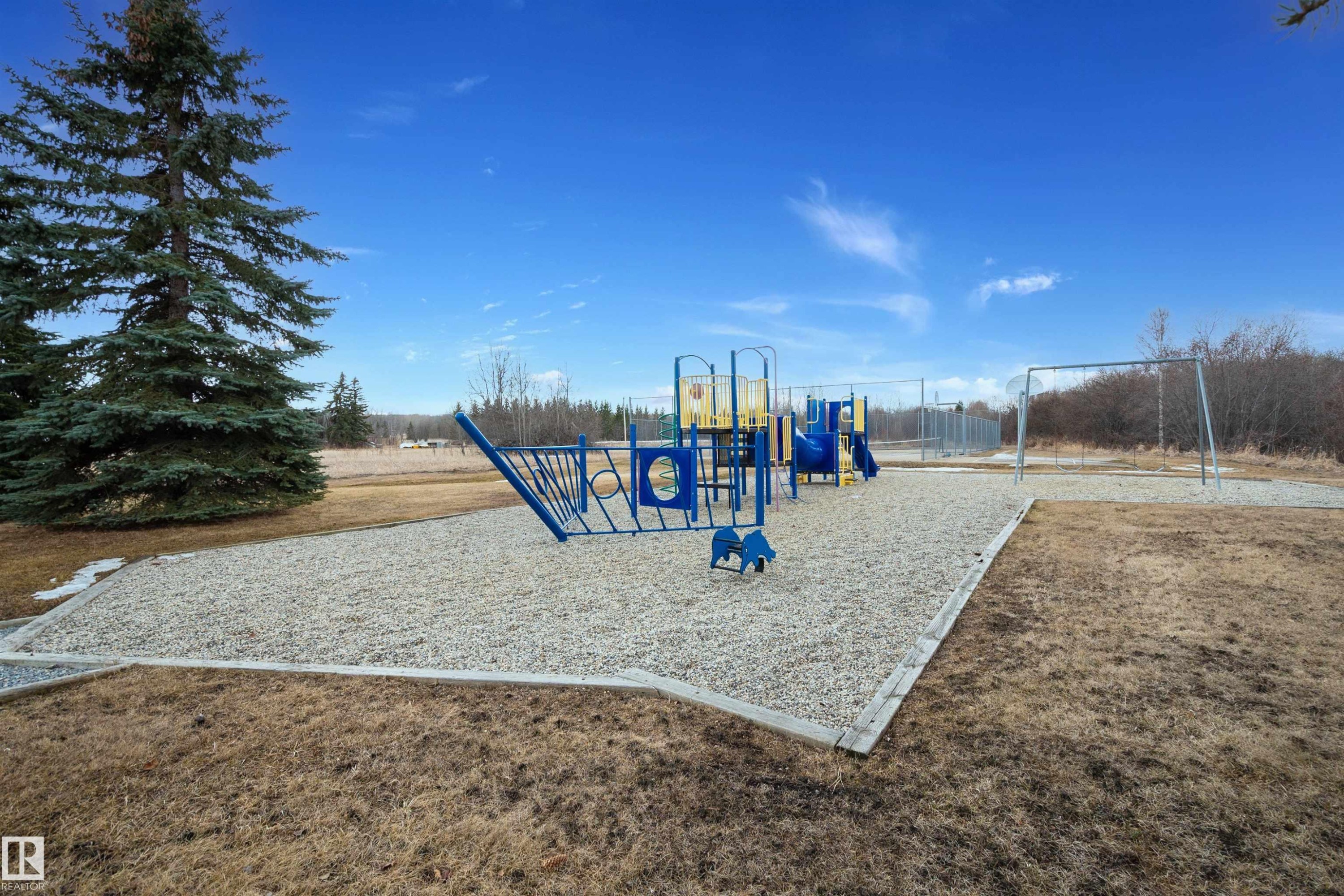 Community amenity featuring a playground with blue and yellow equipment, a swing set, and a gravel surface - 17 Sunset Harbour, Rural Wetaskiwin County, AB - Outdoor With View