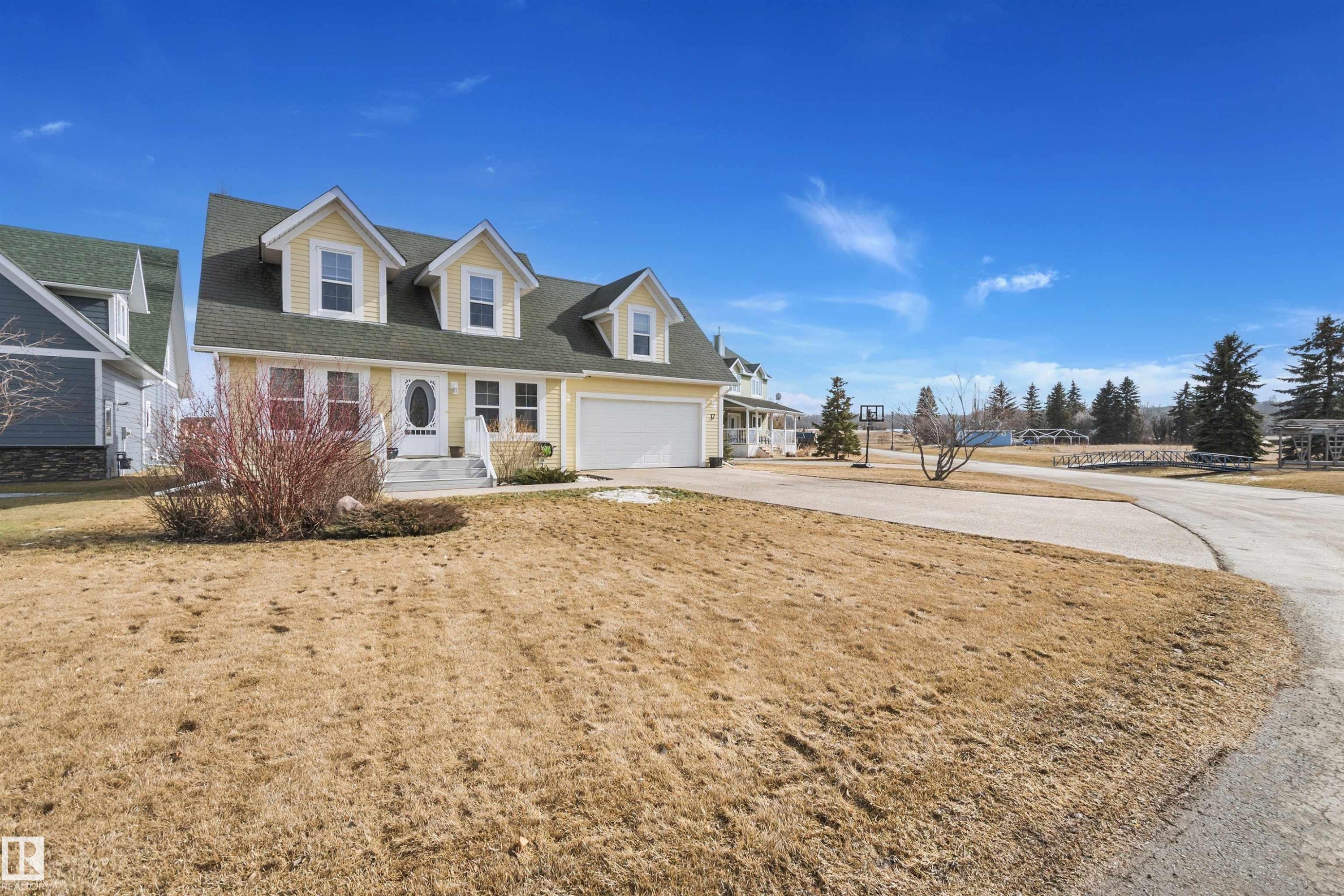 This property features a charming yellow exterior with a dark green roof and white trim - 17 Sunset Harbour, Rural Wetaskiwin County, AB - Outdoor