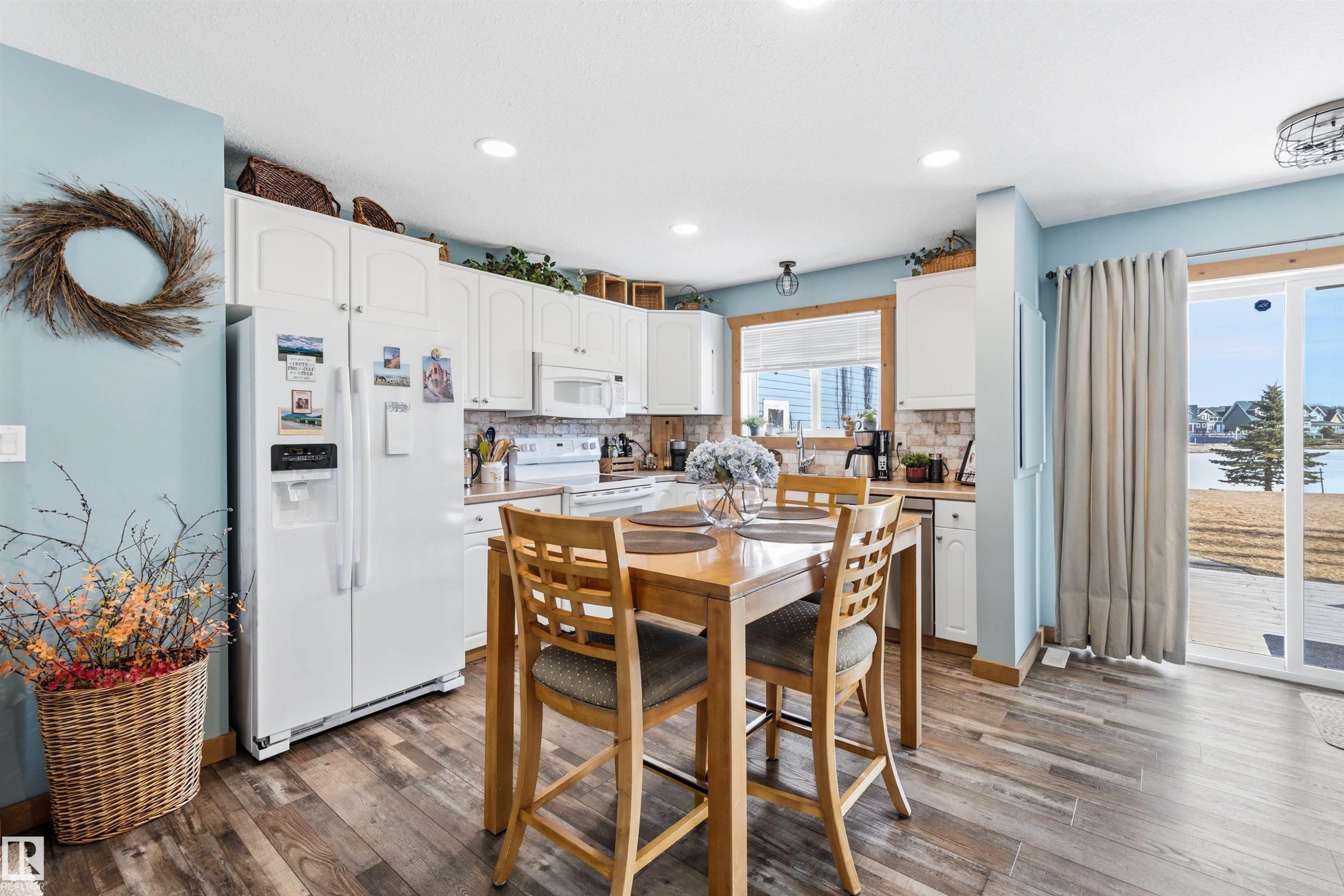 The kitchen features white cabinetry, a white refrigerator, and a sliding glass door leading to the outdoors - 17 Sunset Harbour, Rural Wetaskiwin County, AB - Indoor