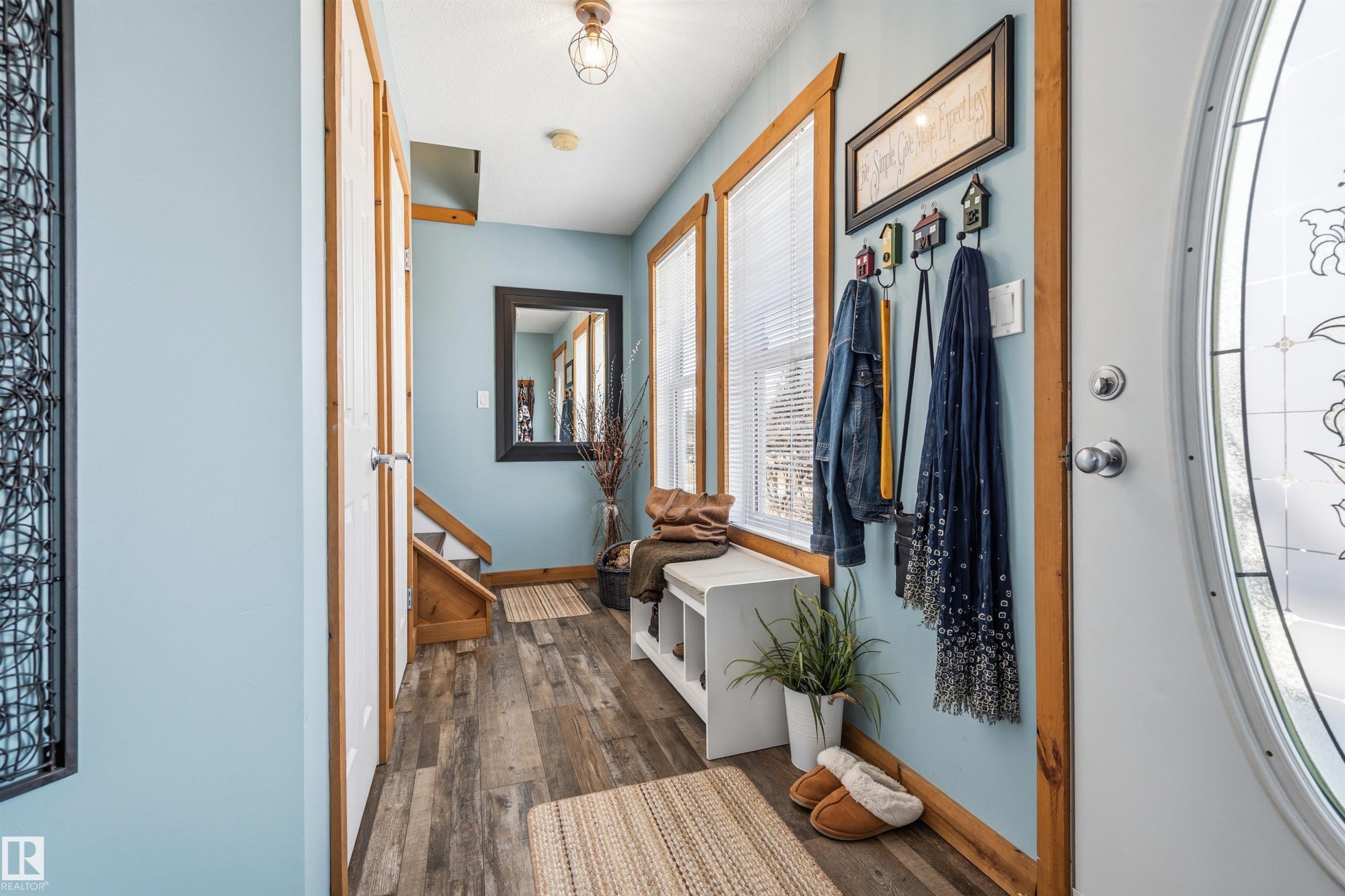 Entryway featuring hardwood-style flooring, light blue walls, and natural wood trim around windows and doorways - 17 Sunset Harbour, Rural Wetaskiwin County, AB - Indoor Photo Showing Other Room