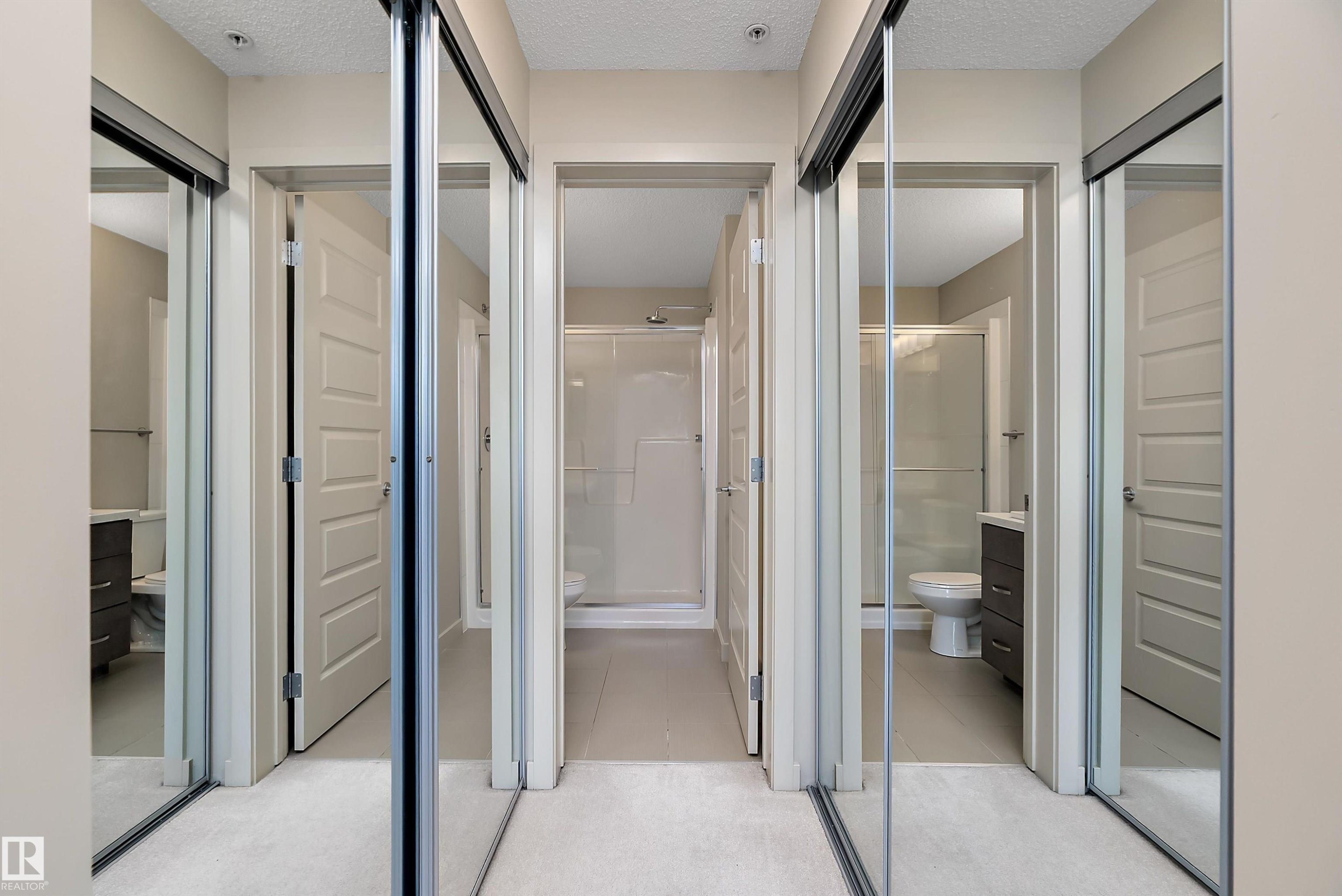 This hallway features mirrored sliding closet doors and light-colored walls - 309 4008 Savaryn Drive, Edmonton, AB - With Balcony With Exterior