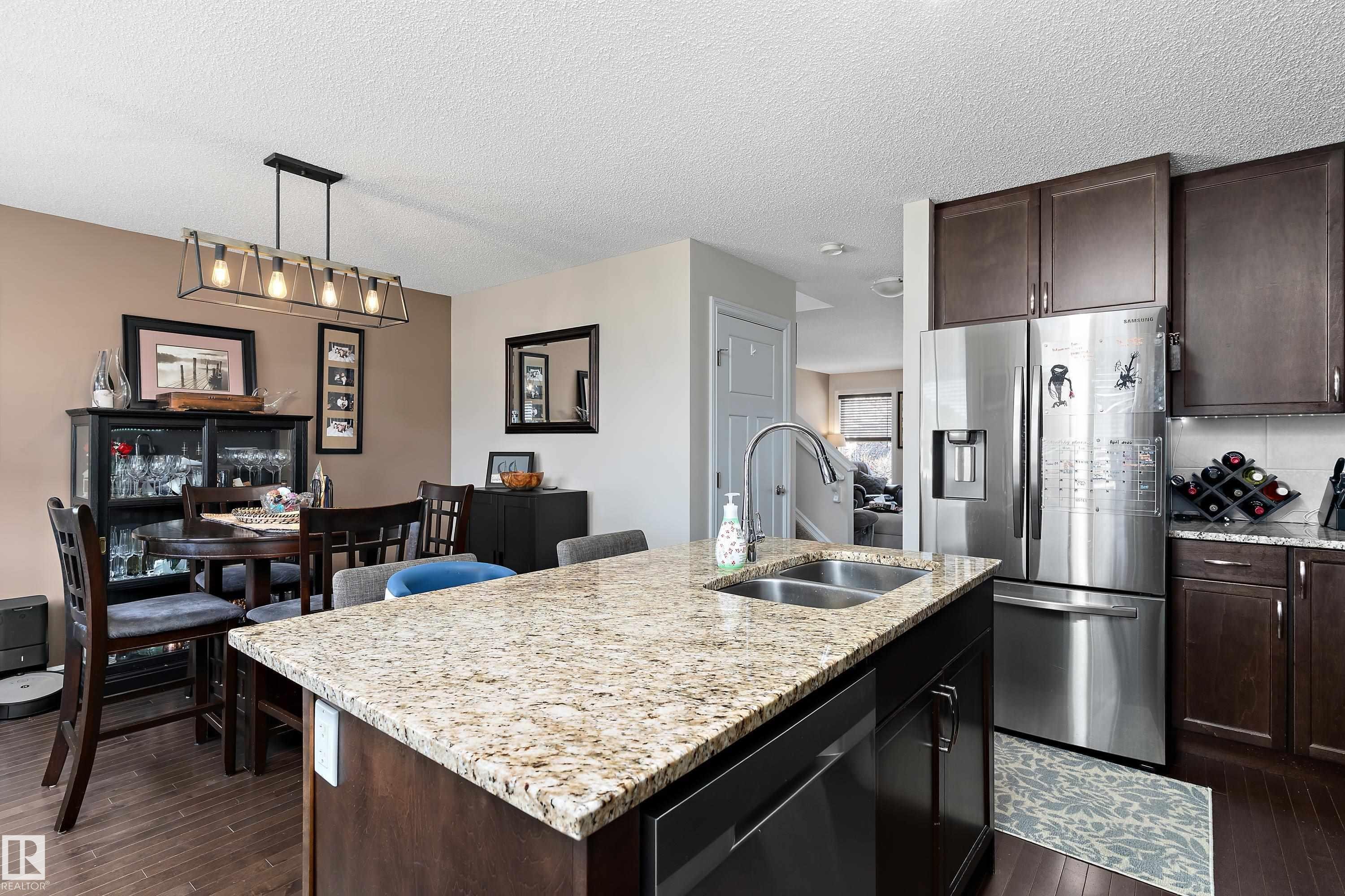 Kitchen featuring granite countertops, stainless steel appliances, dark wood cabinetry, and a double basin sink - 6822 Cardinal Link, Edmonton, AB - Indoor Photo Showing Kitchen With Double Sink