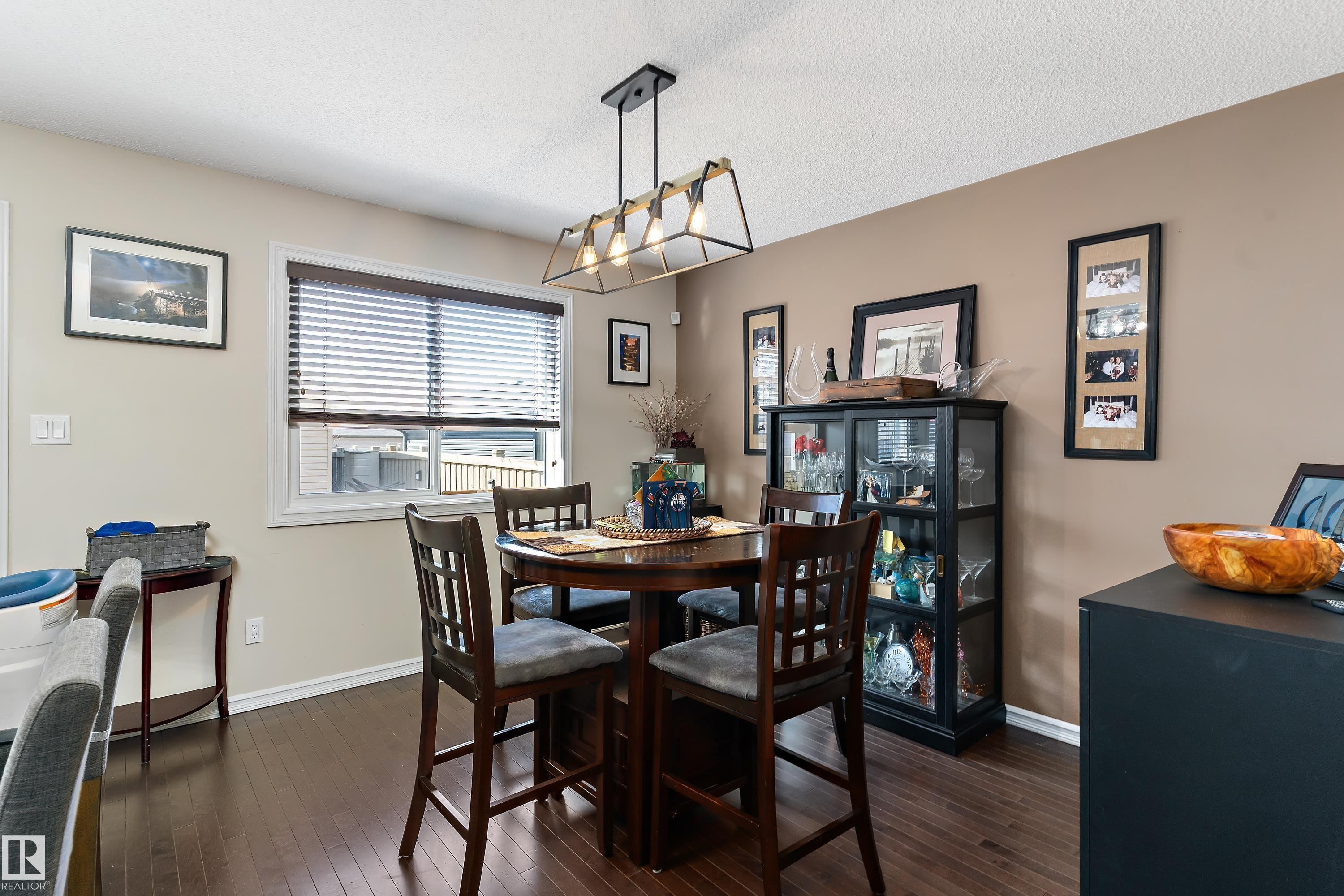 The property features rich hardwood flooring, a window with blinds, and a modern ceiling light fixture - 6822 Cardinal Link, Edmonton, AB - Indoor Photo Showing Dining Room