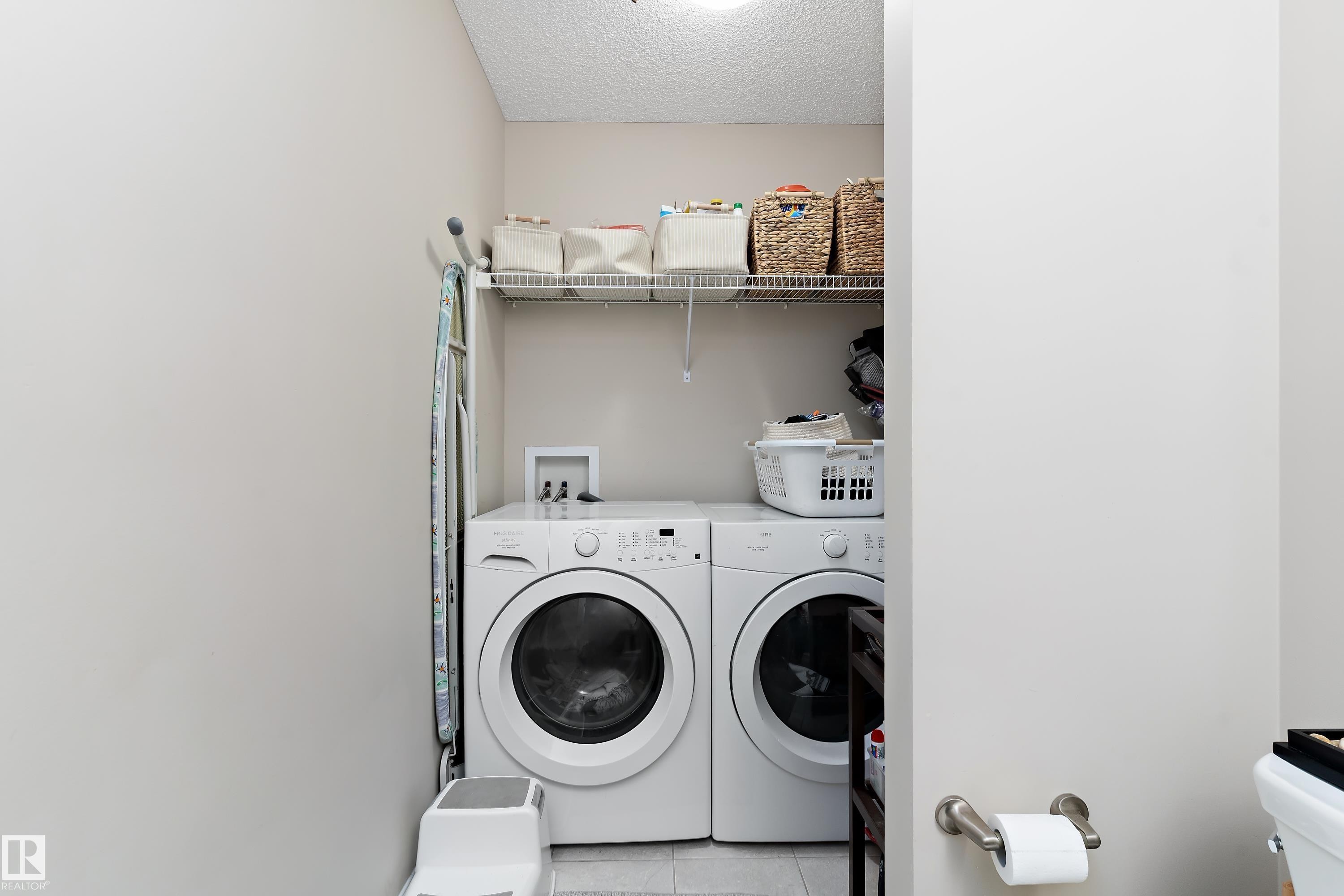 Dedicated laundry area featuring a washer and dryer, an overhead wire shelf for storage, and light-colored walls - 6822 Cardinal Link, Edmonton, AB - Indoor Photo Showing Laundry Room