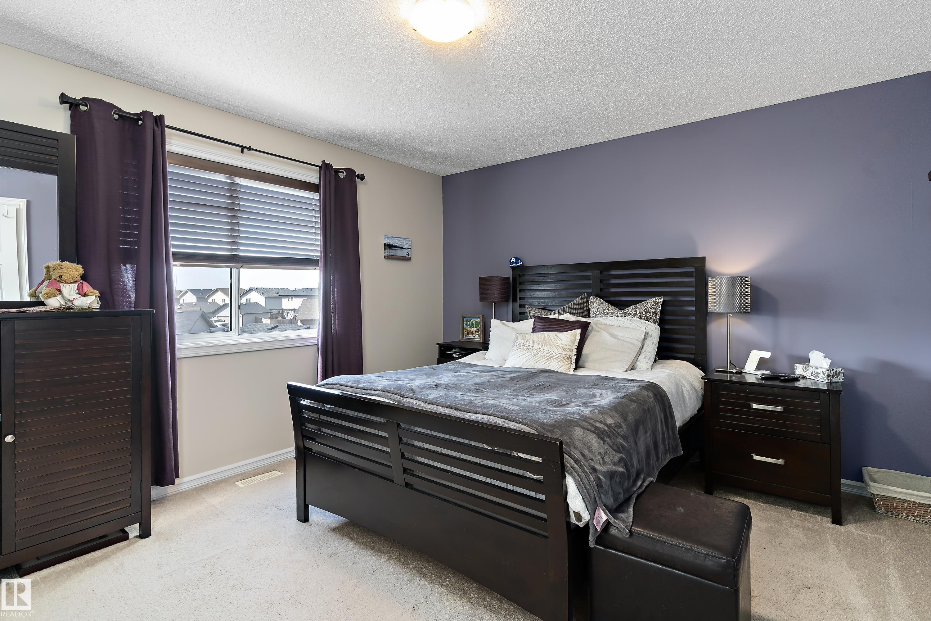 This room features a window with blinds and dark curtains, light-colored carpeting, and a ceiling light fixture - 6822 Cardinal Link, Edmonton, AB - Indoor Photo Showing Bedroom