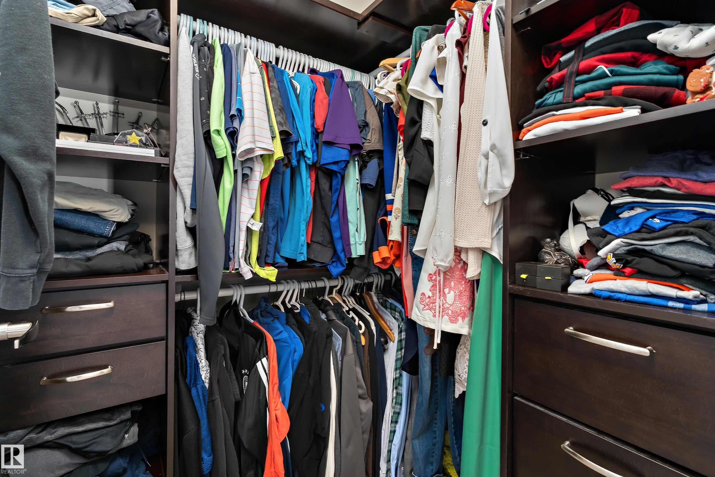 Custom closet system featuring dark wood cabinetry, integrated shelving, and hanging rods - 6822 Cardinal Link, Edmonton, AB - Indoor With Storage