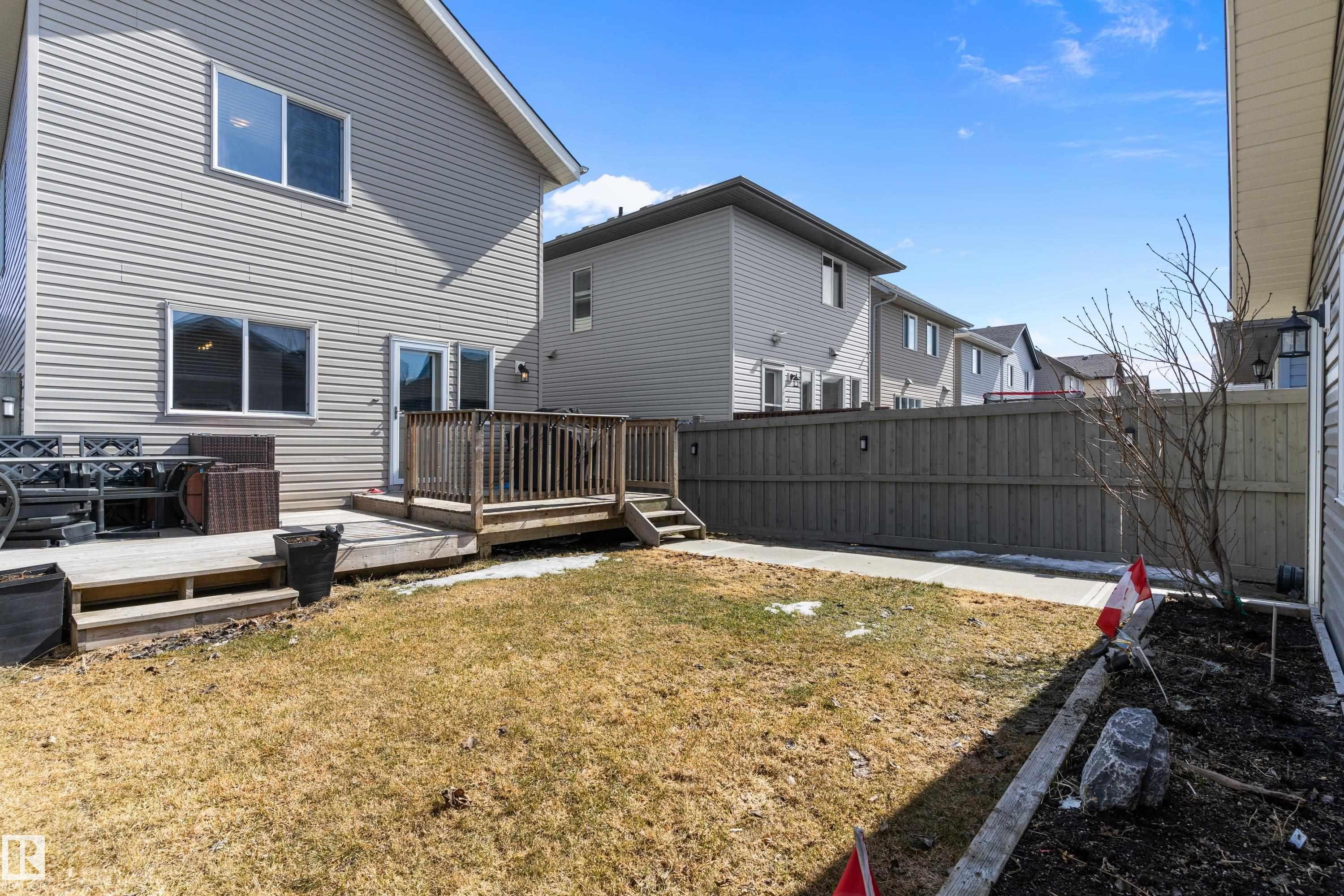 The property features a wooden deck with railing, a patio door providing direct access to the interior, and an expanse of yard space - 6822 Cardinal Link, Edmonton, AB - Outdoor With Deck Patio Veranda With Exterior