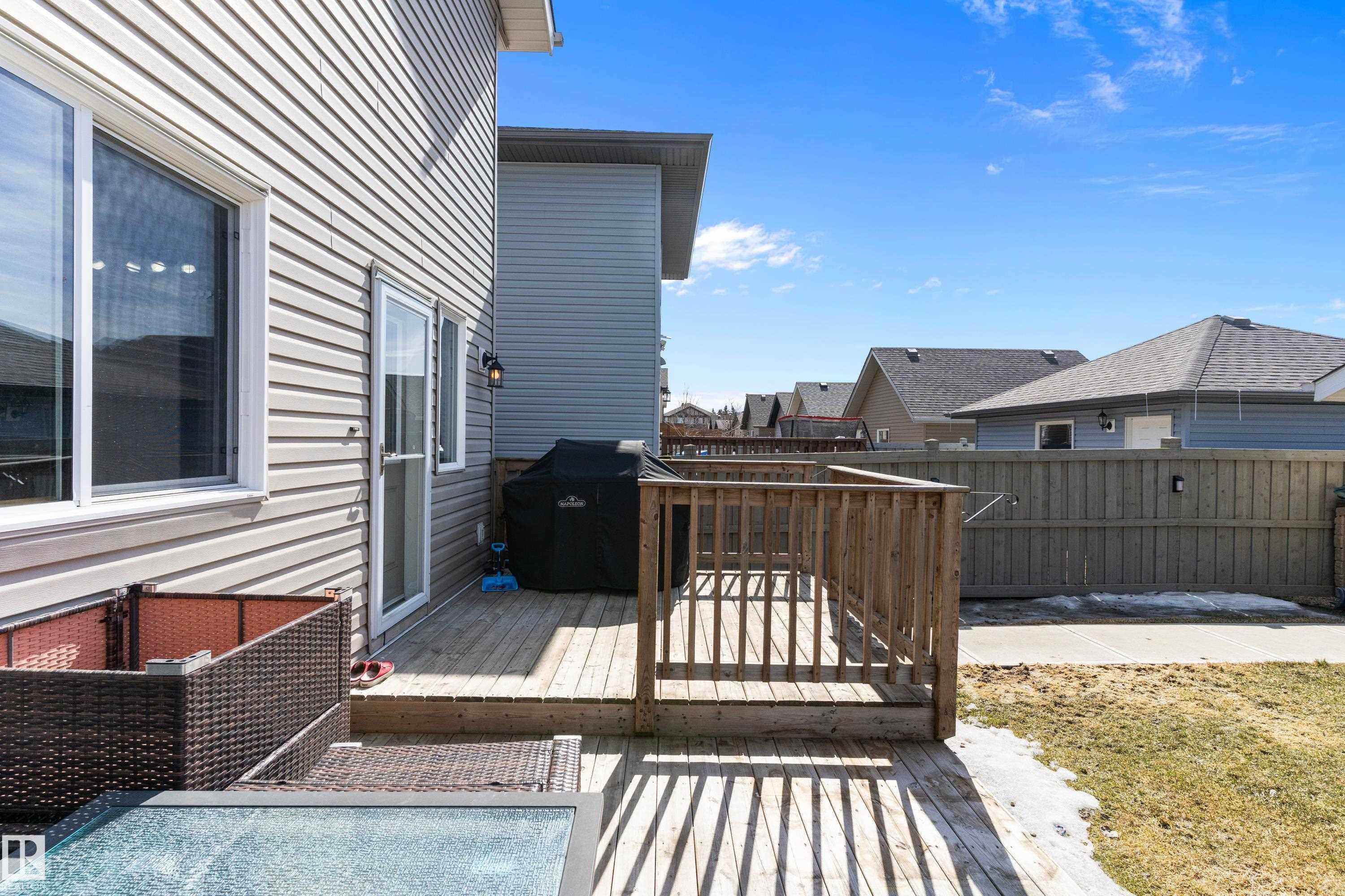 The property features a wooden deck with railing, accessible via a glass-paneled door - 6822 Cardinal Link, Edmonton, AB - Outdoor With Deck Patio Veranda With Exterior