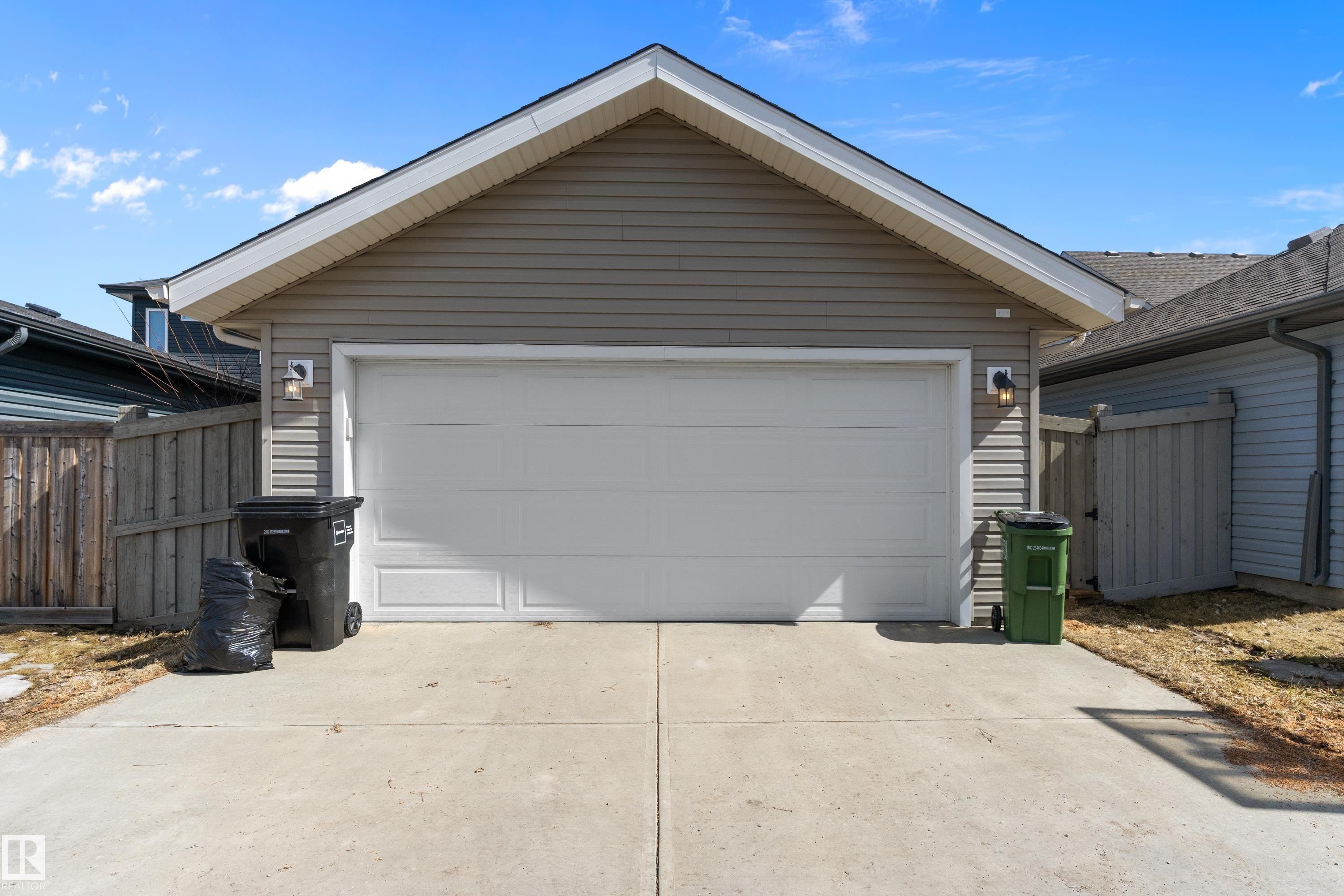 The property features an attached garage with a white garage door, gray siding, and a concrete driveway - 6822 Cardinal Link, Edmonton, AB - Outdoor With Exterior