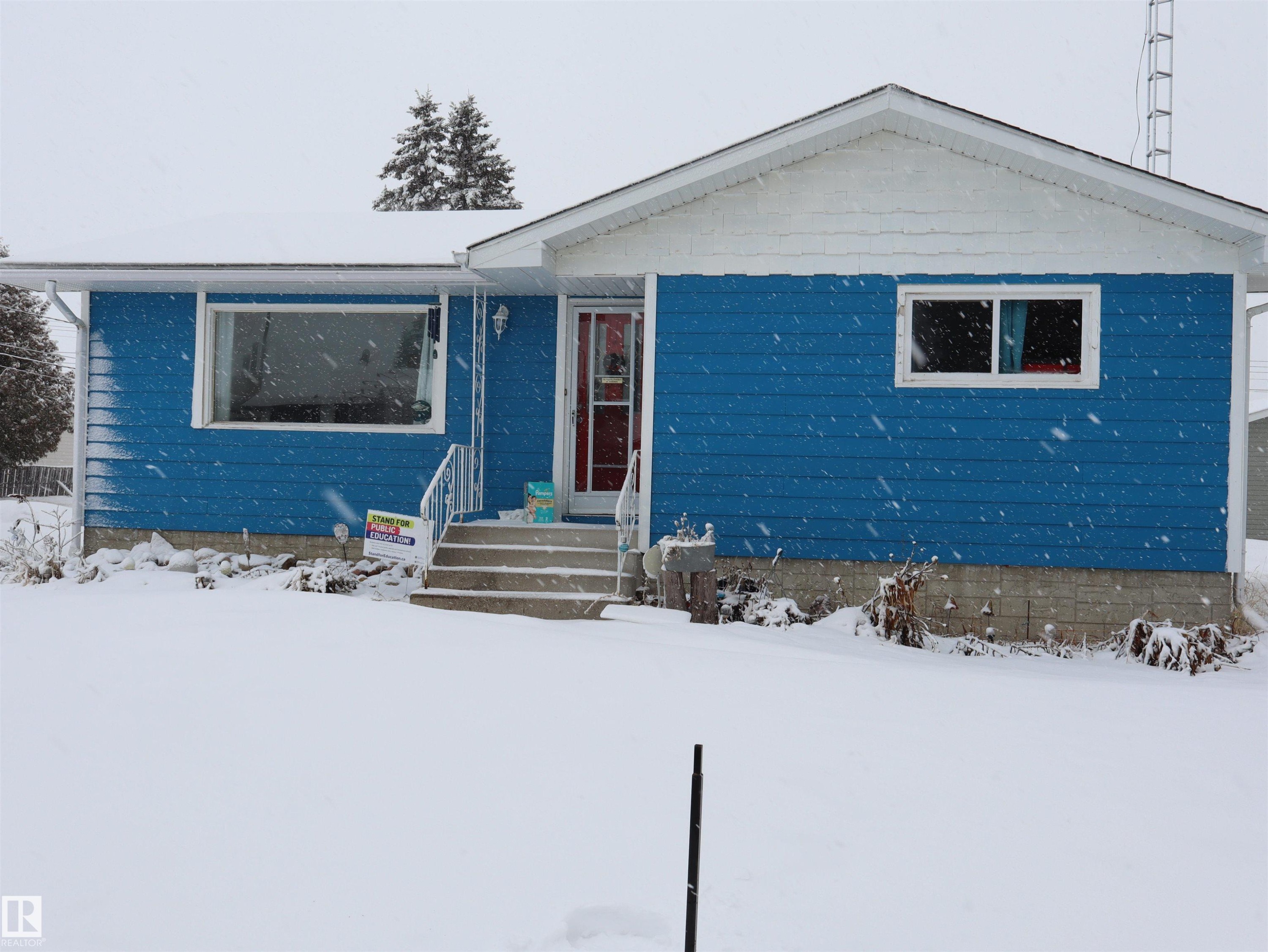 The property features blue horizontal siding with white trim and a concrete foundation - 4315 56 Avenue, Barrhead, AB - Outdoor