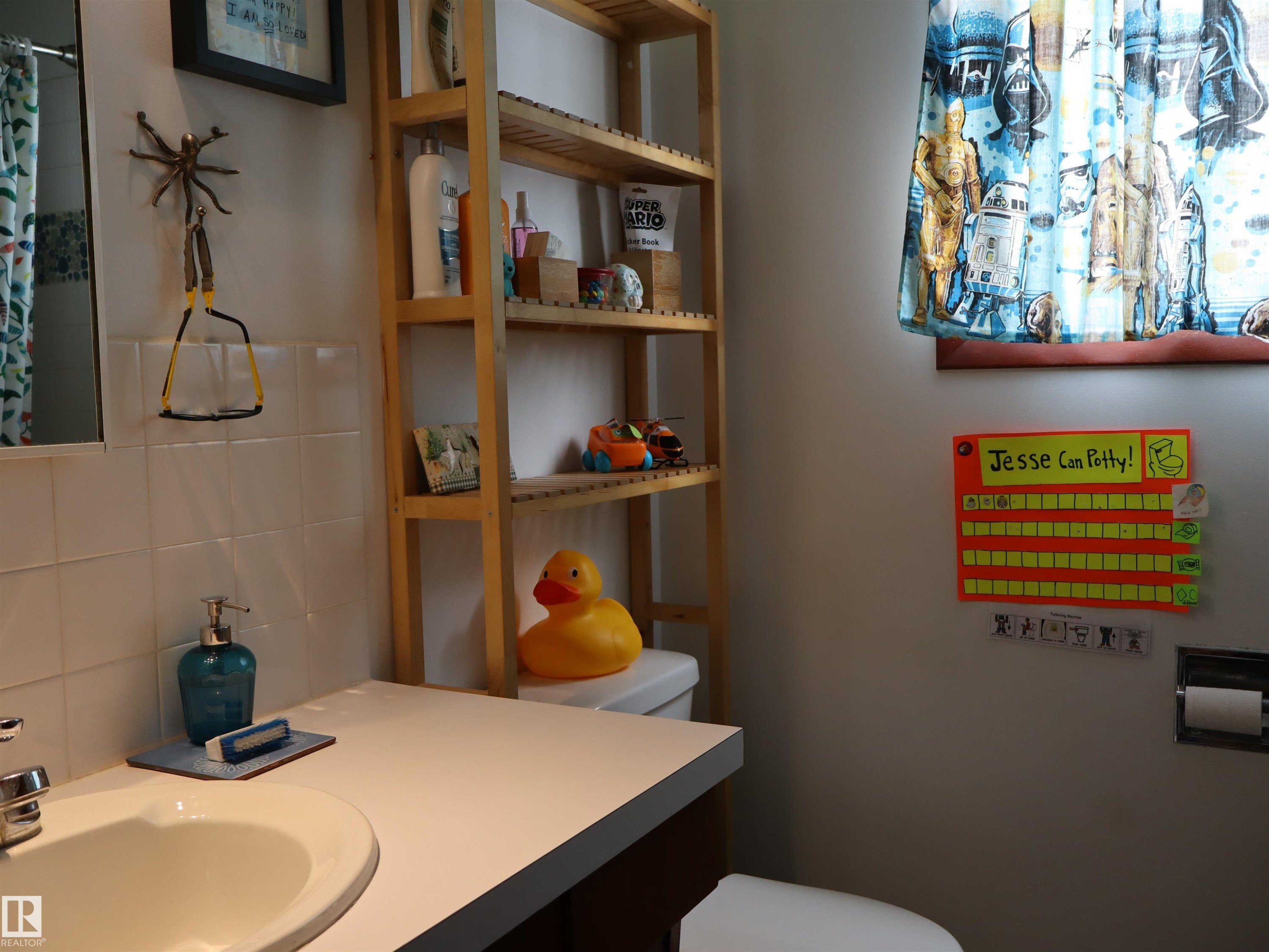 Bathroom featuring a white vanity with an integrated sink, a wall-mounted mirror, and white tiled walls - 4315 56 Avenue, Barrhead, AB - Indoor Photo Showing Bathroom