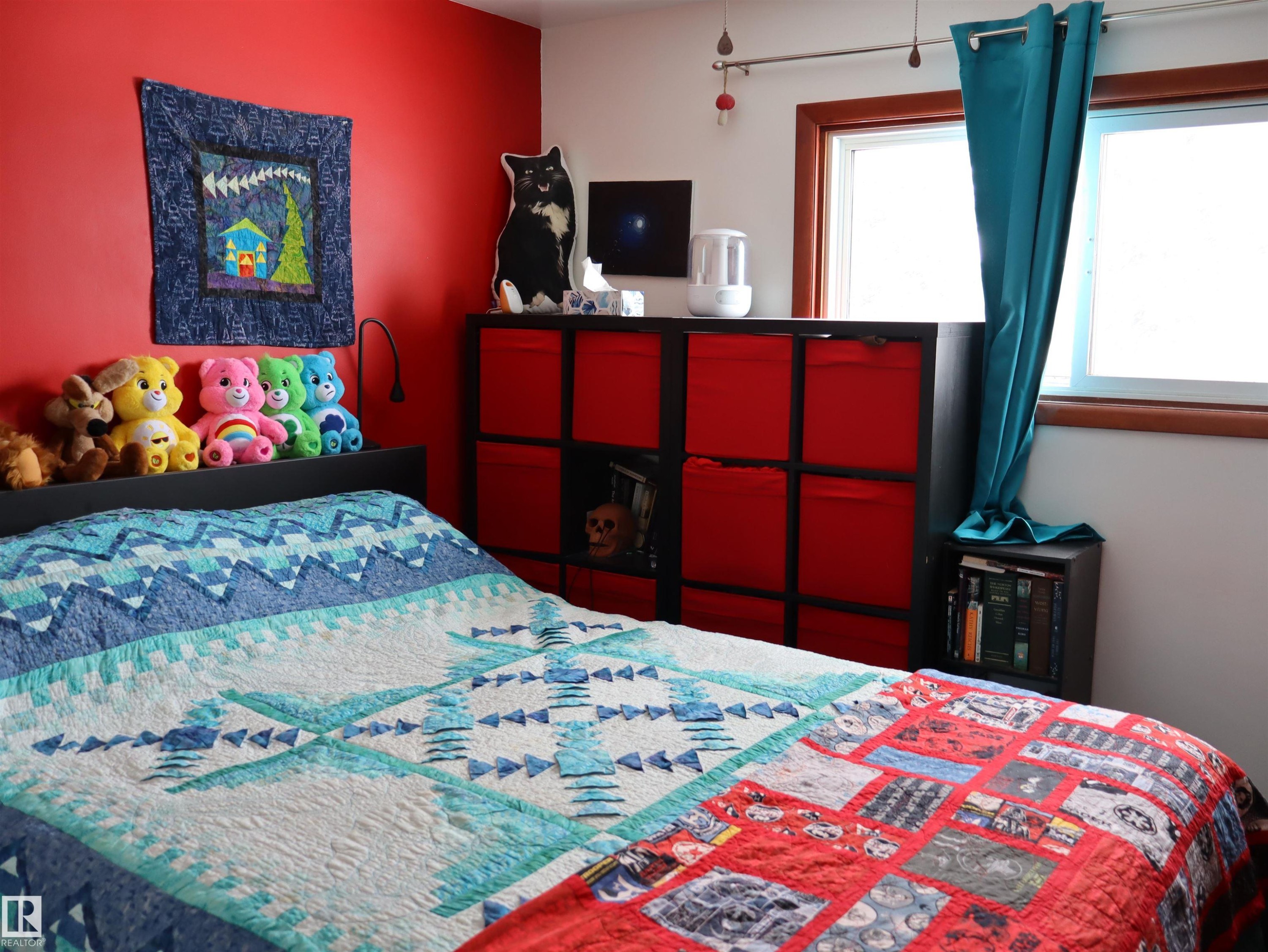 This bedroom features bright red accent walls and white walls, with windows providing natural light - 4315 56 Avenue, Barrhead, AB - Indoor Photo Showing Bedroom