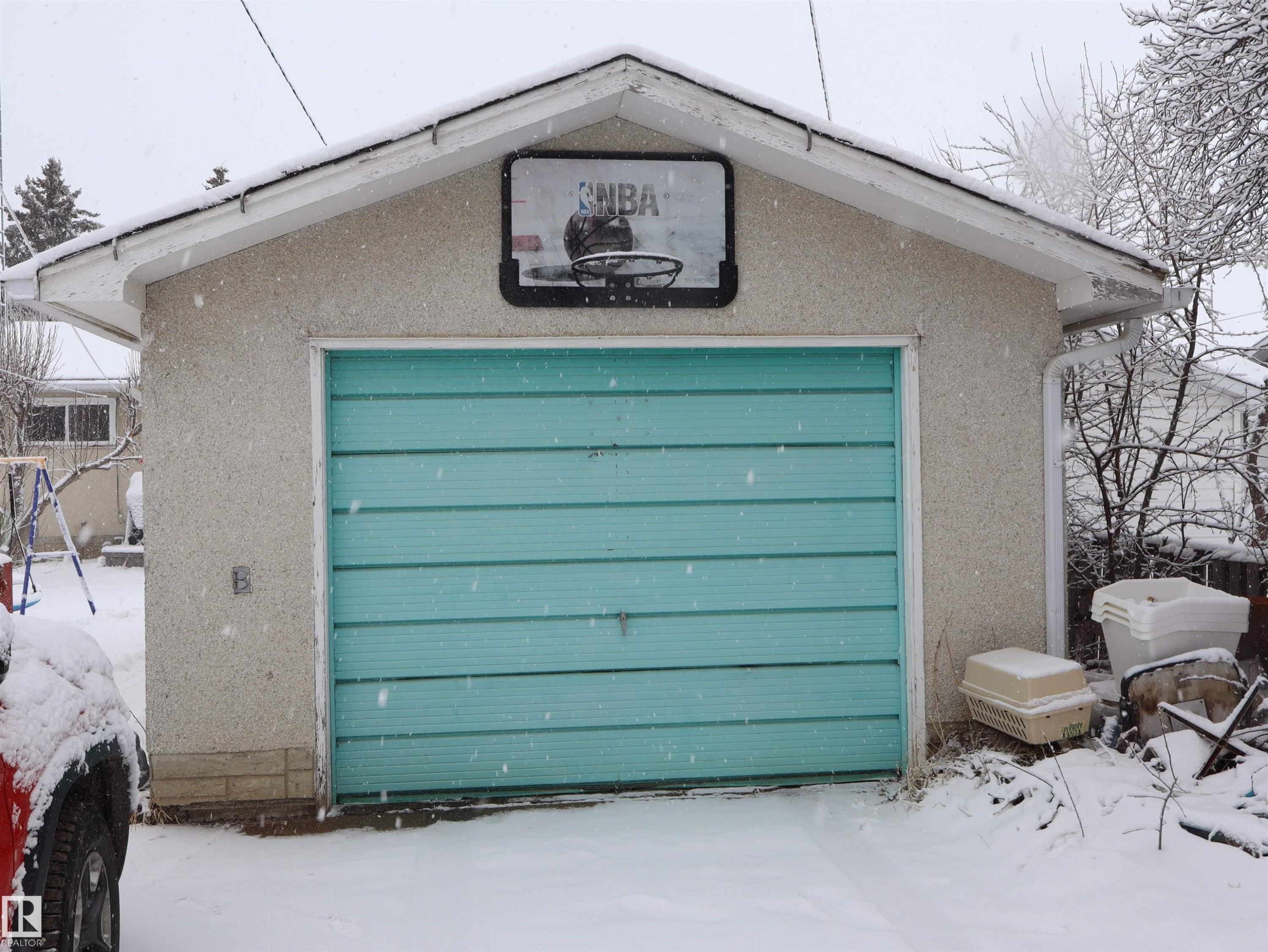 Detached garage with a light blue sectional door and a textured stucco exterior finish - 4315 56 Avenue, Barrhead, AB - Outdoor