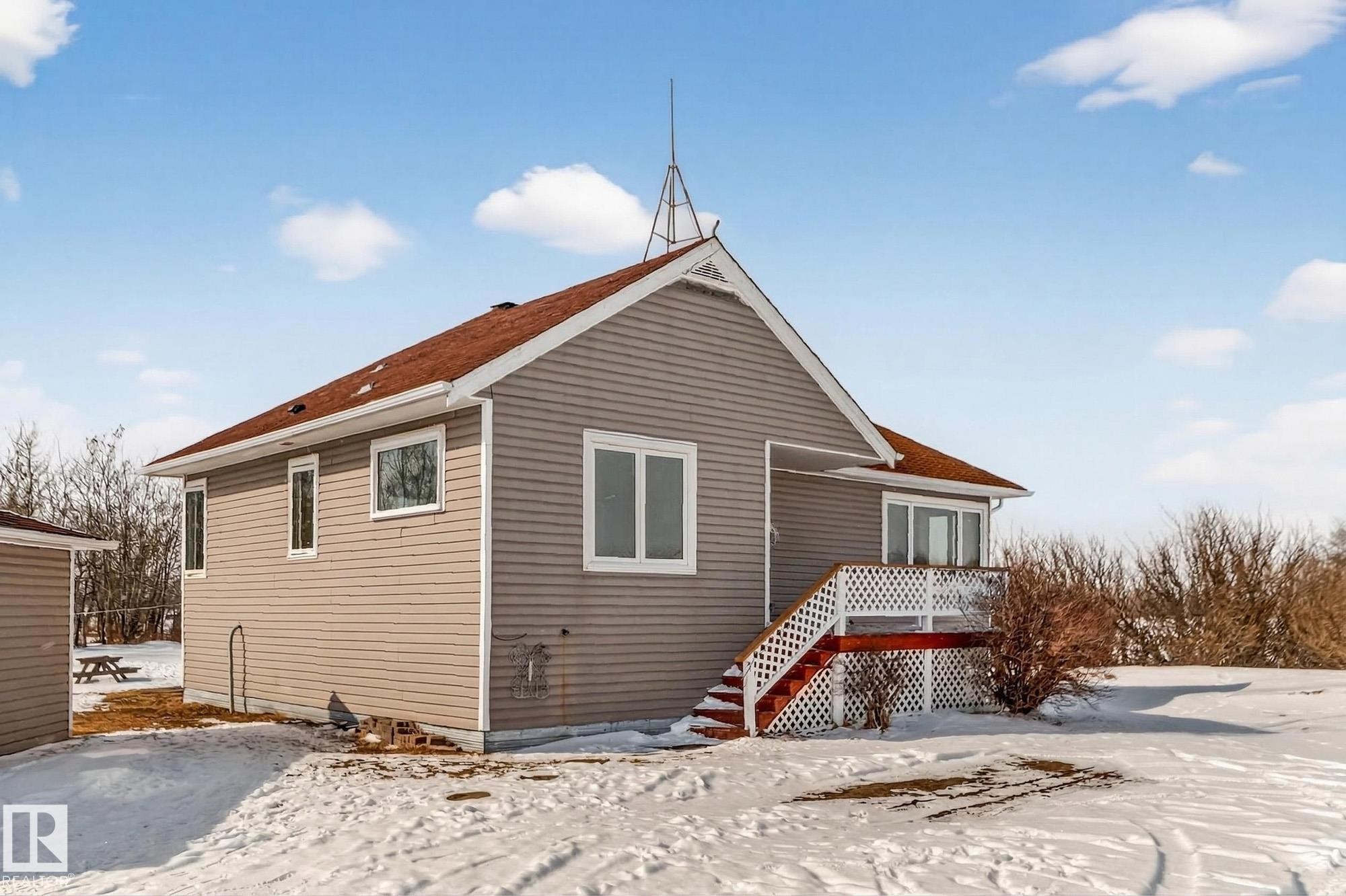 The property features a peaked roof with red shingles, light grey siding, and white window frames - 160068 Twp 531, Rural Lamont County, AB - Outdoor With Exterior