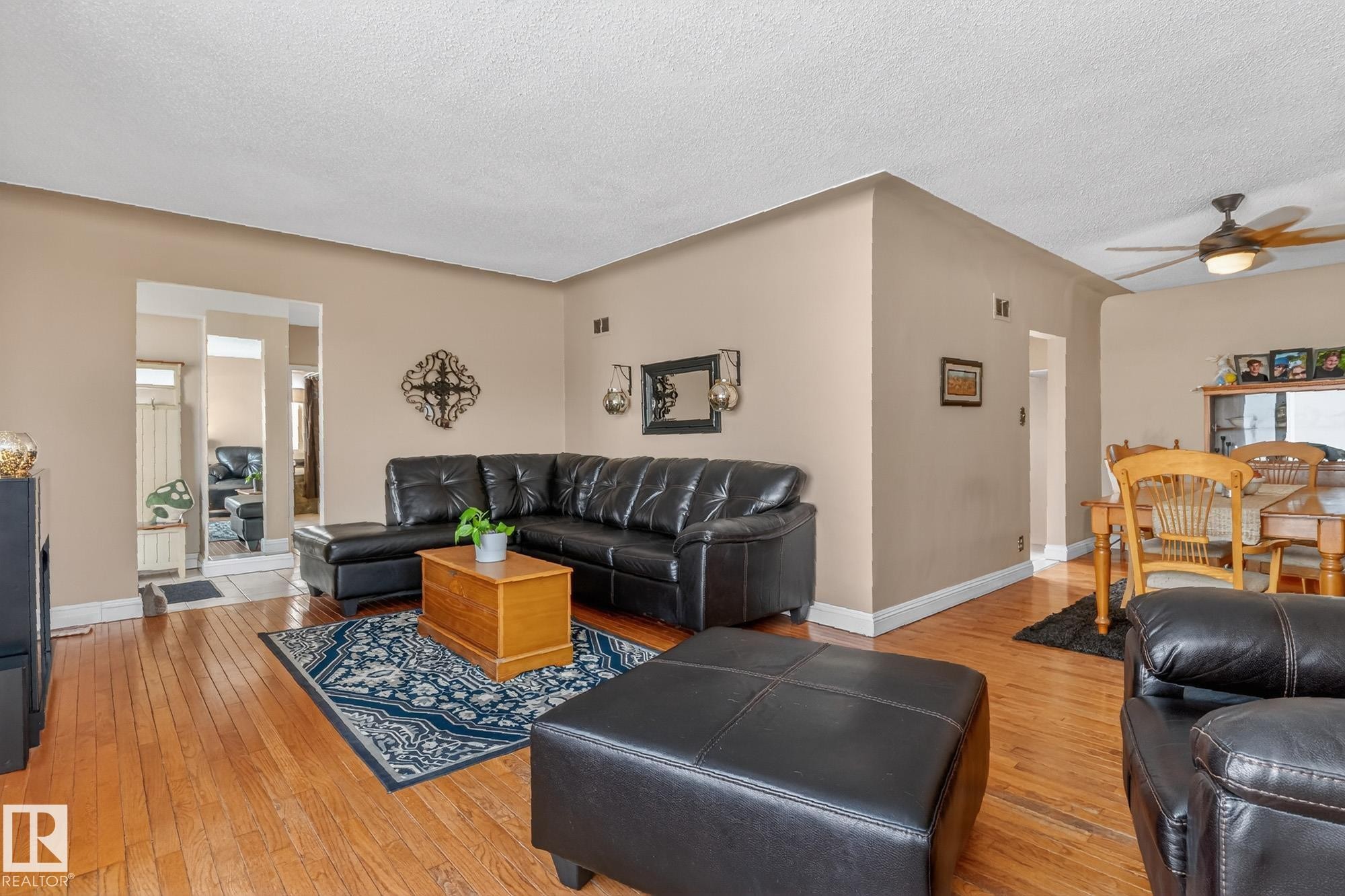 This living area features hardwood floors and a ceiling fan, with a dining area visible in the background - 160068 Twp 531, Rural Lamont County, AB - Indoor Photo Showing Living Room